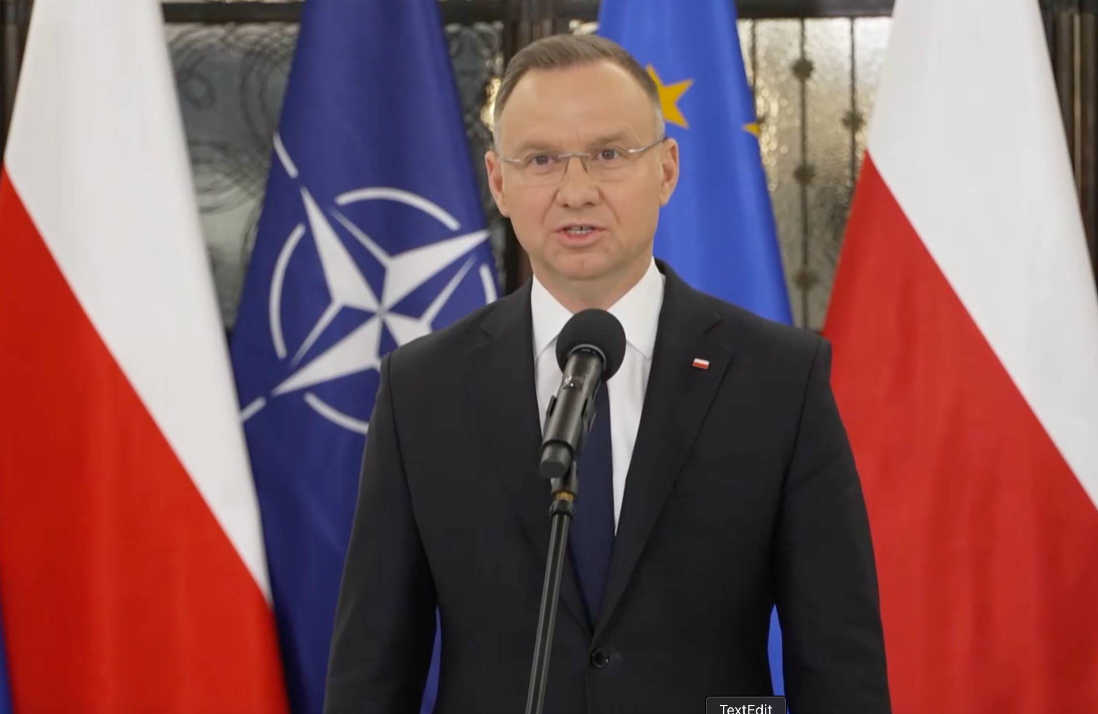 Andrzej Duda przemawia na korytarzu sejmowym, w tle za nim flagi Polski, UE oraz NATO