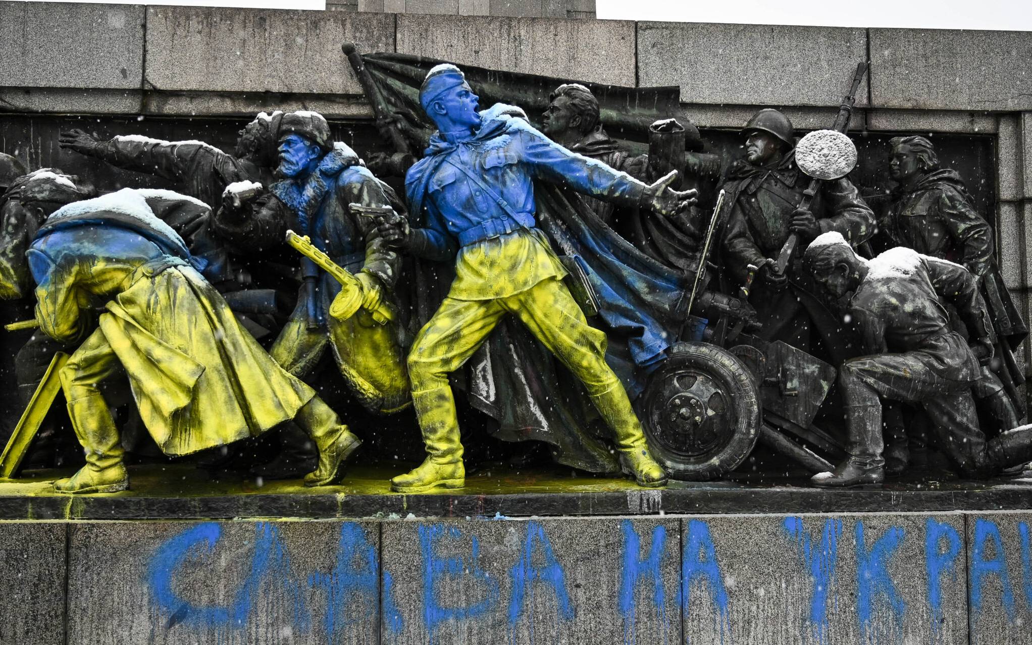 This photograph taken on February 27, 2022 shows the figures of Soviet soldiers freshly painted with Ukranian flag colours at the base of the Soviet Army monument in Sofia, on February 27, 2022 in reaction to Russia's invasion of Ukraine. - Ukrainian forces said they had fought off a Russian incursion in Ukraine's second-biggest city on February 27, 2022, as both sides said they were ready for talks to halt a conflict that has forced hundreds of thousands of people to flee their homes. Already a number of EU countries -- such as Bulgaria, the Czech Republic, Estonia, Germany and Poland -- have closed their airspace to Russian flights, forcing westbound Russian planes to make enormous diversions. (Photo by Nikolay DOYCHINOV / AFP)
