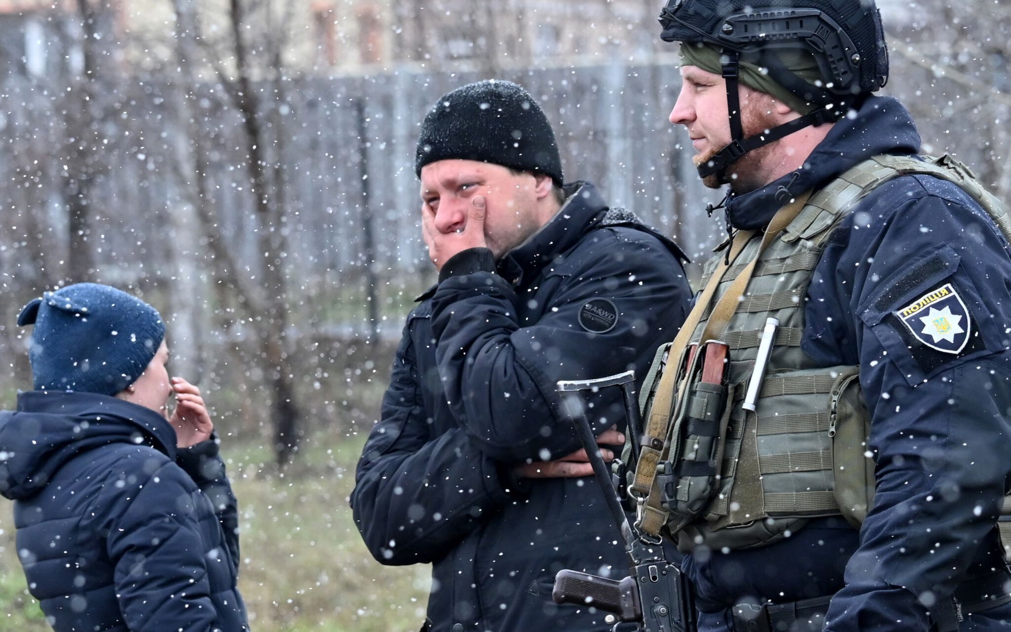 People react as they gather close to a mass grave in the town of Bucha, just northwest of the Ukrainian capital Kyiv on April 3, 2022. - President Volodymyr Zelensky accused Russia of committing genocide and attempting to eliminate the "whole nation" of Ukraine, a day after the discovery of mass graves and apparently executed civilians near Kyiv. (Photo by Sergei SUPINSKY / AFP)