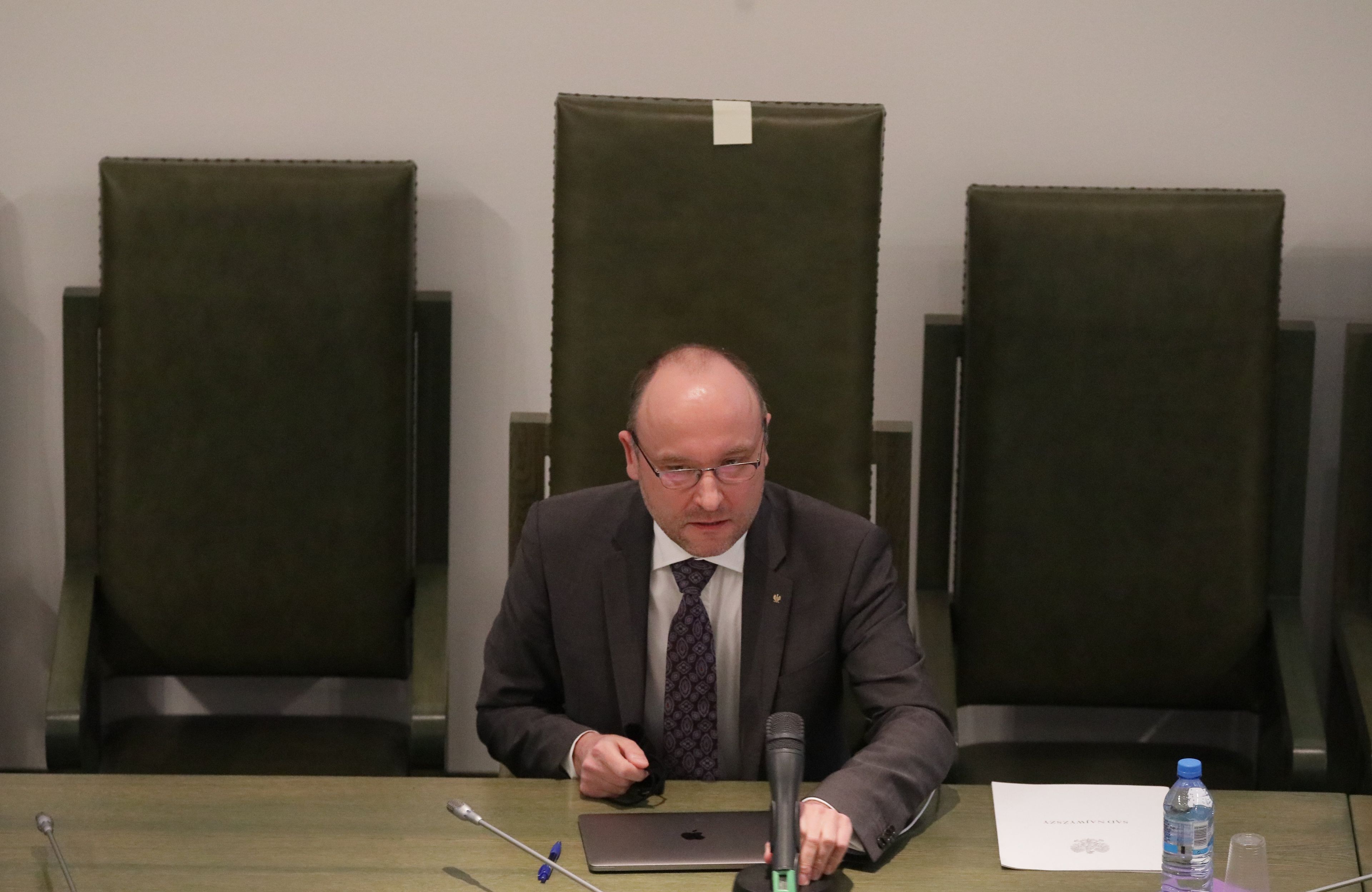 Mężczyzna w okularach siedzi przy stole sędziowskim