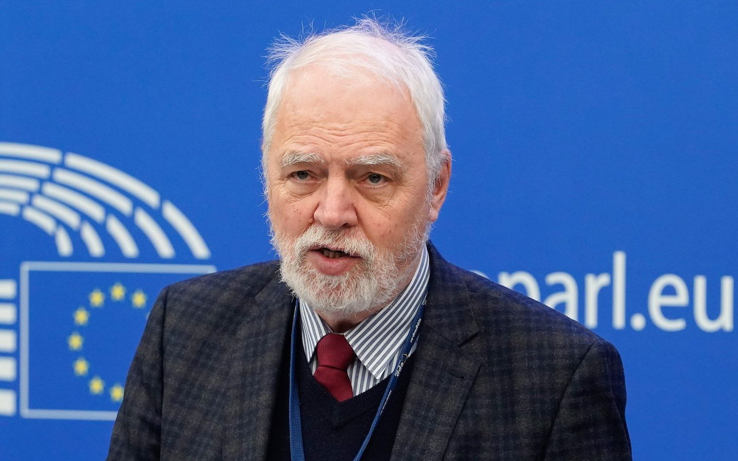 Europoseł PO Jan Olbrycht przemawia w Parlamencie Europejskim. To siwy mężczyzna z siwą brodą obrany w kraciastą marynarkę i bordowy krawat.