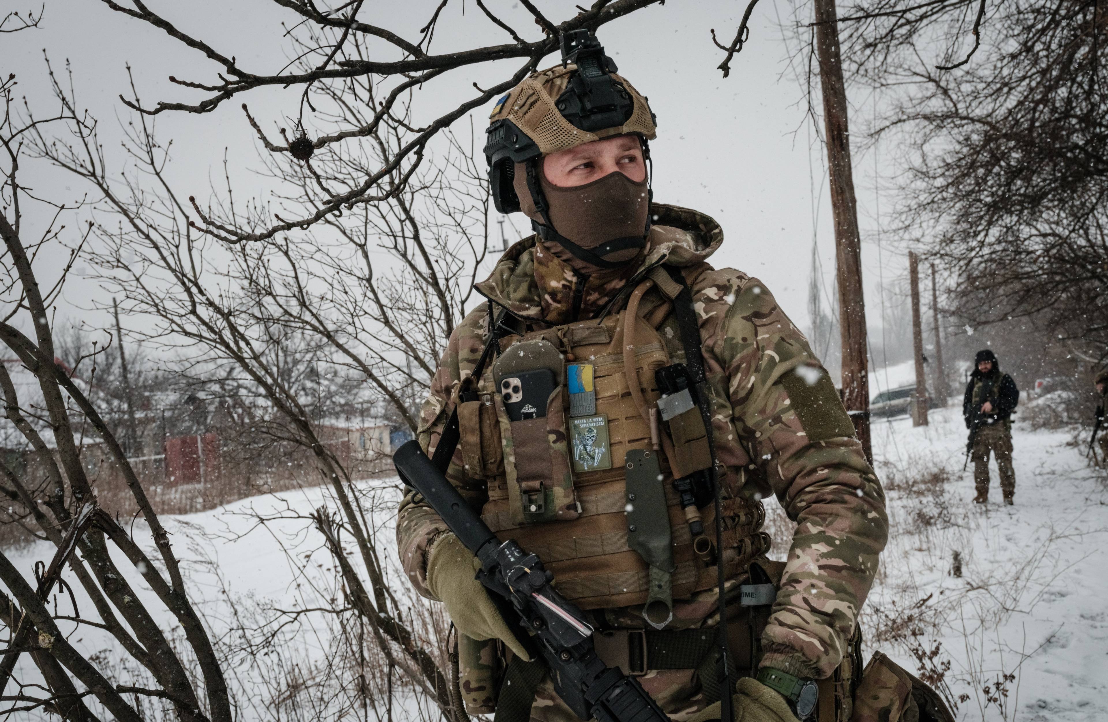 Zołnierz w bojowym rynsztunku z ukraińskimi oznaczeniami stoi na ośnieżonym polu