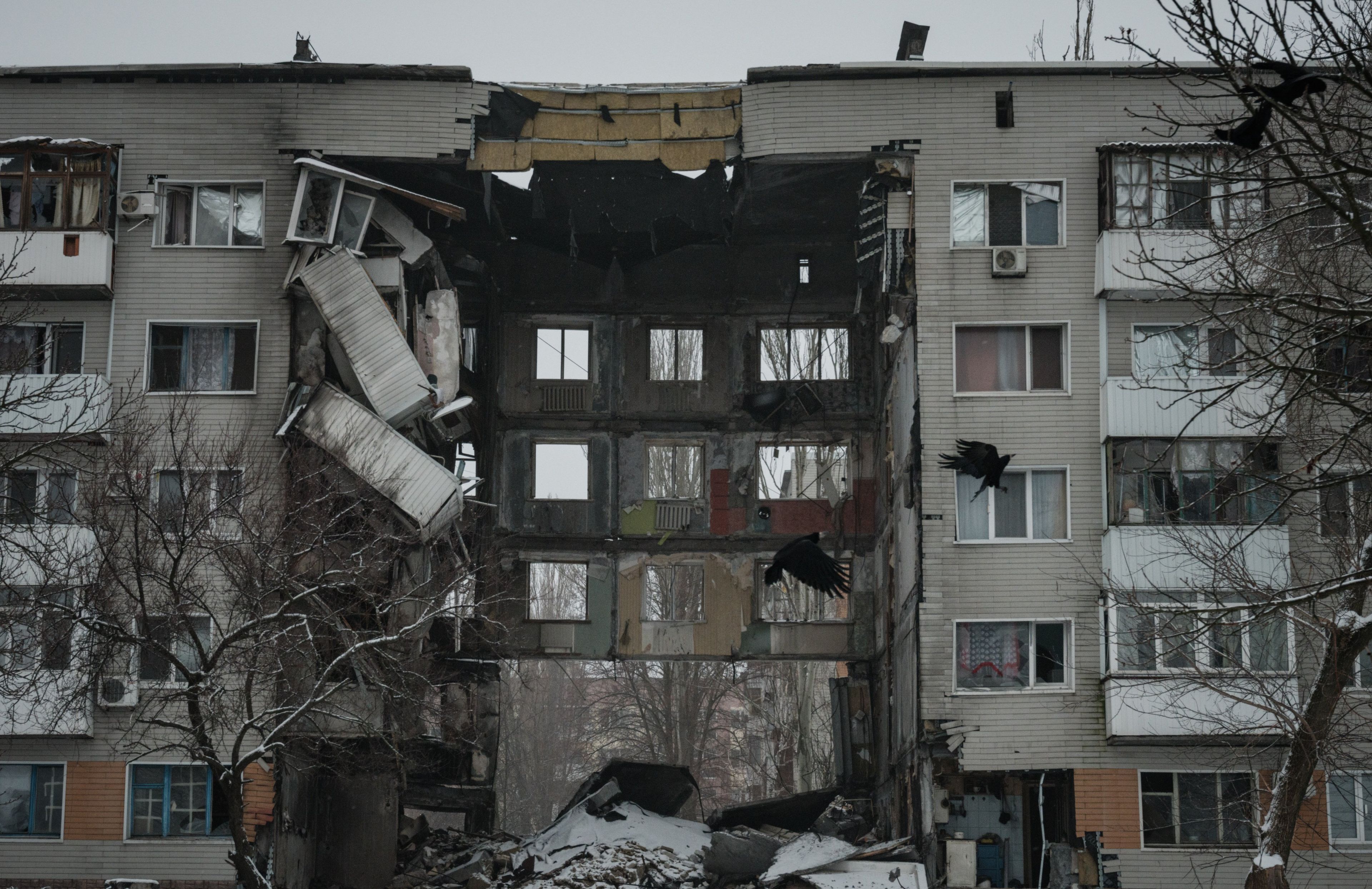 Zima. Blok mieszkalny rozbity pociskami i czarne ptaki