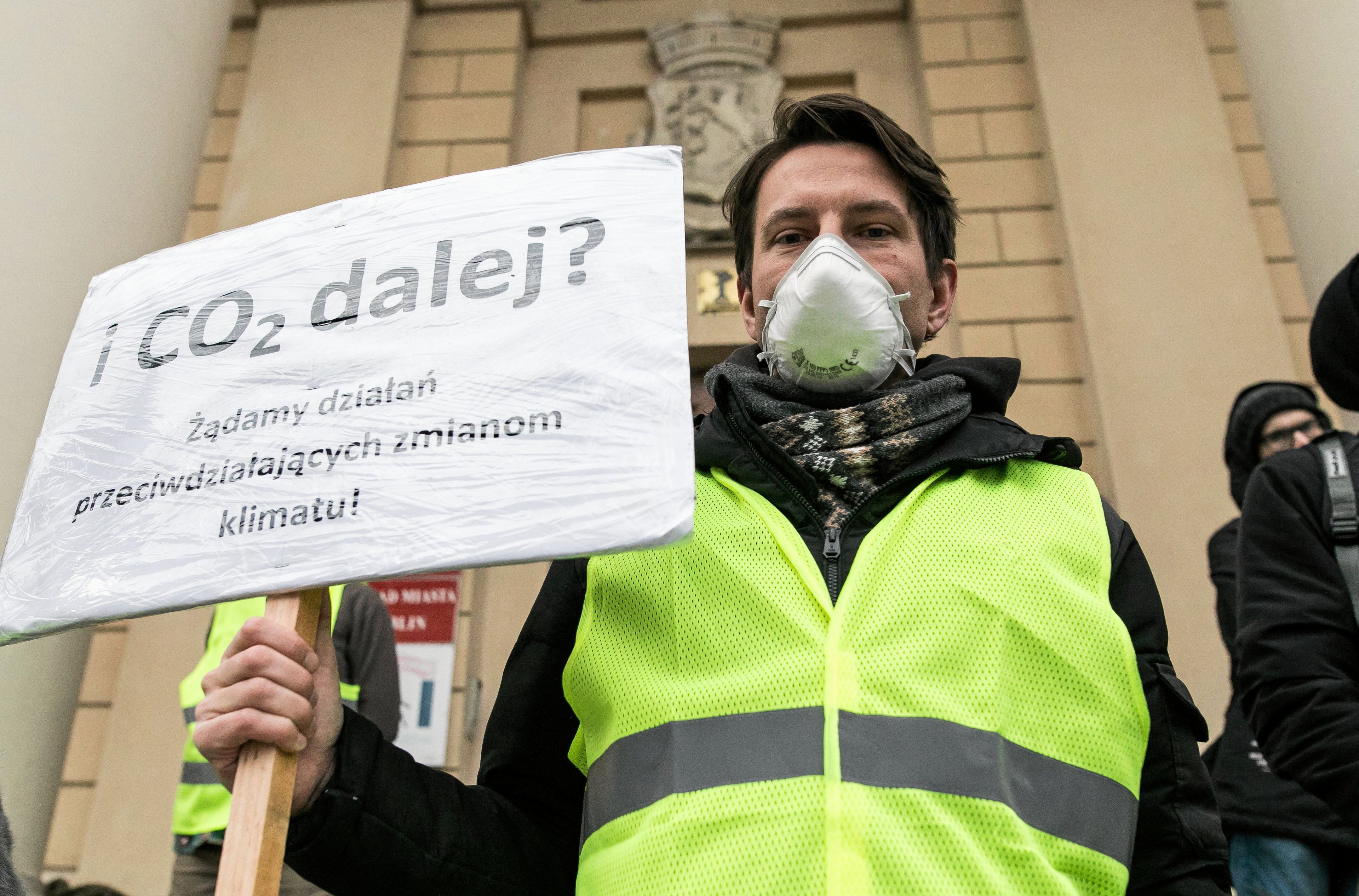 Mężczyzna w zielonej kamizelce odblaskowej z banerem I CO2 dalej?