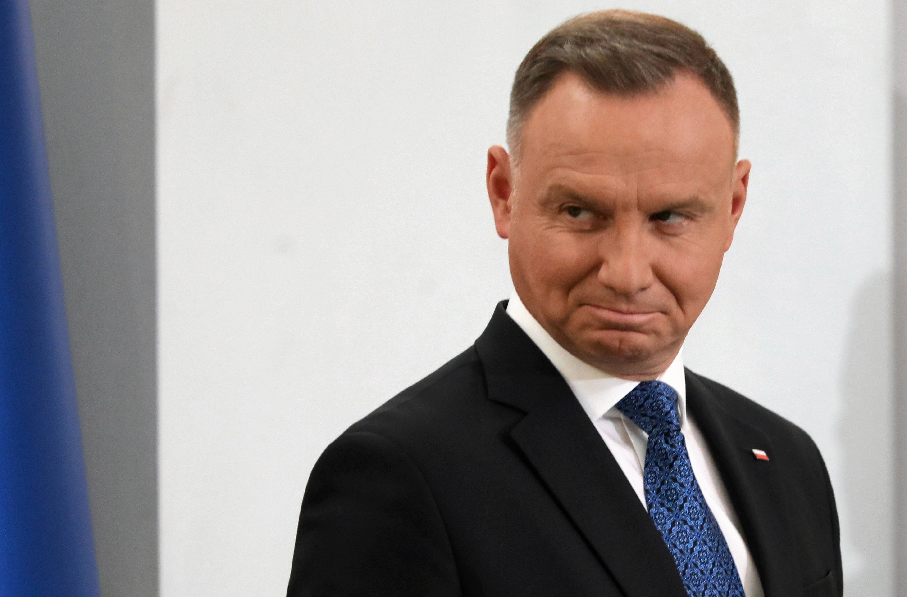 Mężczyzna stoi bokiem i patrzy spode łaba