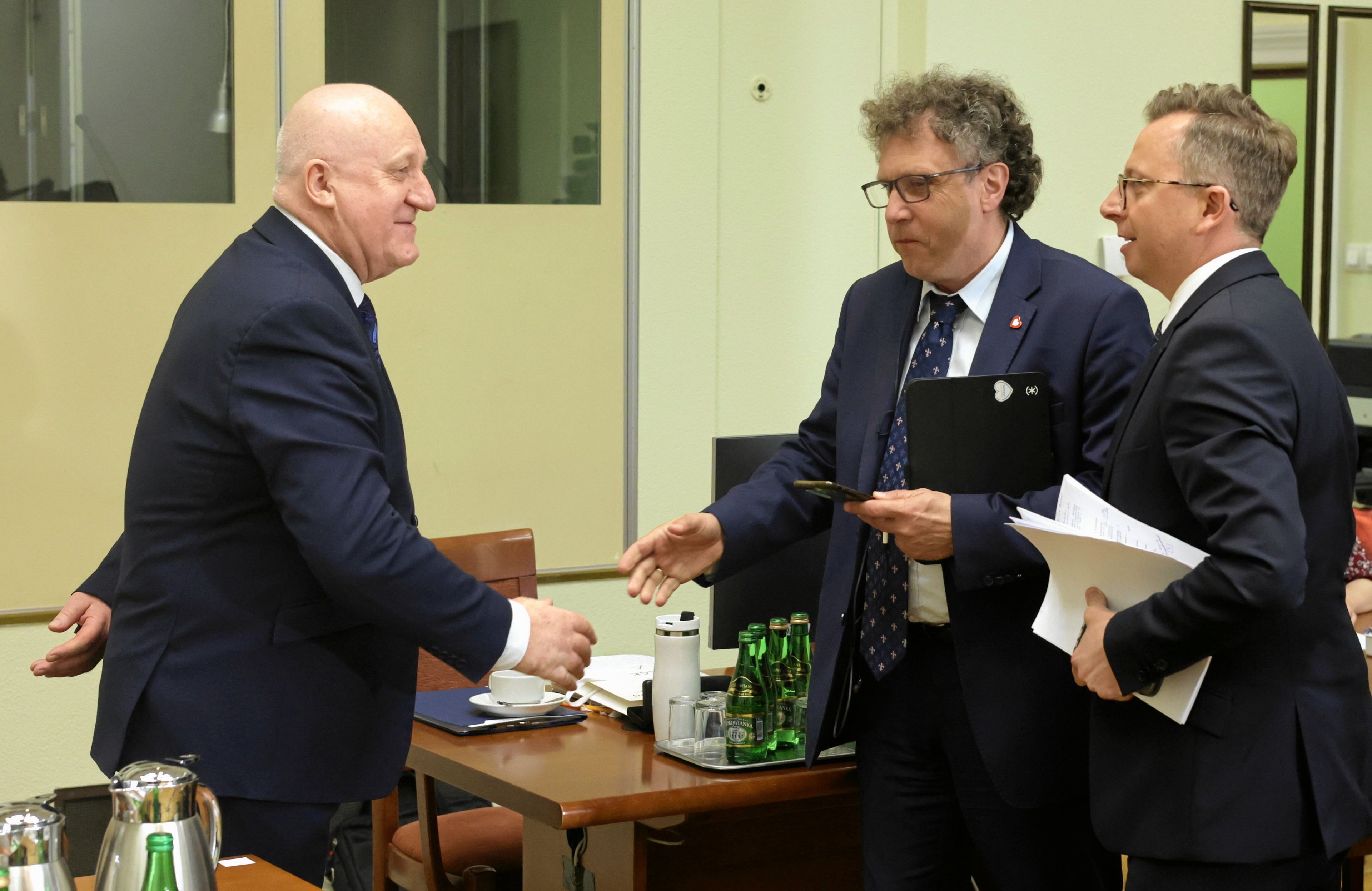 Trzej męzczyźni w garniturach rozmawiają