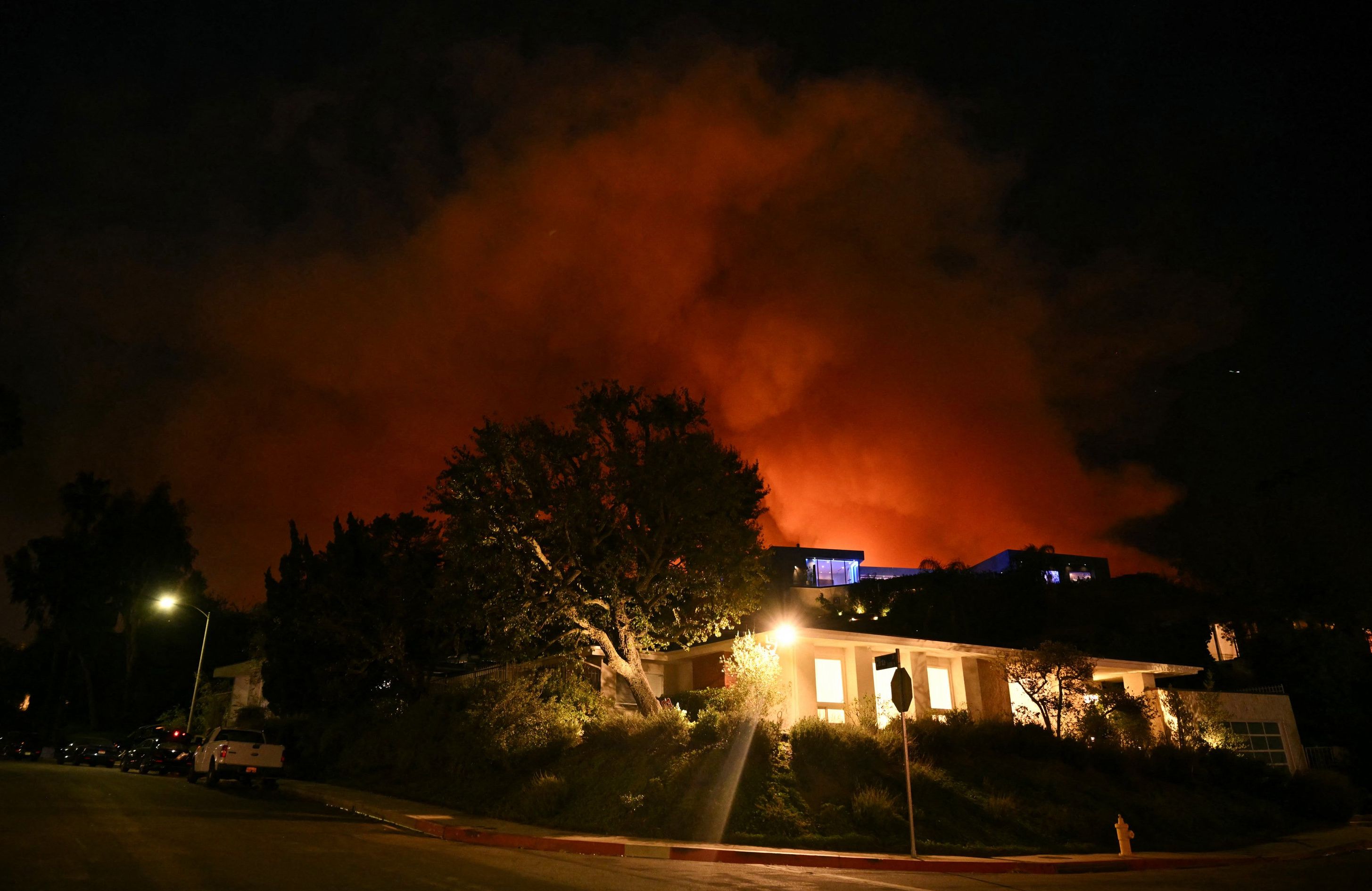 Dym i płomienie z Palisades Fire widać za domem na ulicy Corda drive w kierunku dzielnicy Encino w Los Angeles w Kalifornii, 10 stycznia 2025 r. Ogromne pożary, które pochłonęły całe dzielnice i wysiedliły tysiące ludzi, zabiły co najmniej 10 osób.
