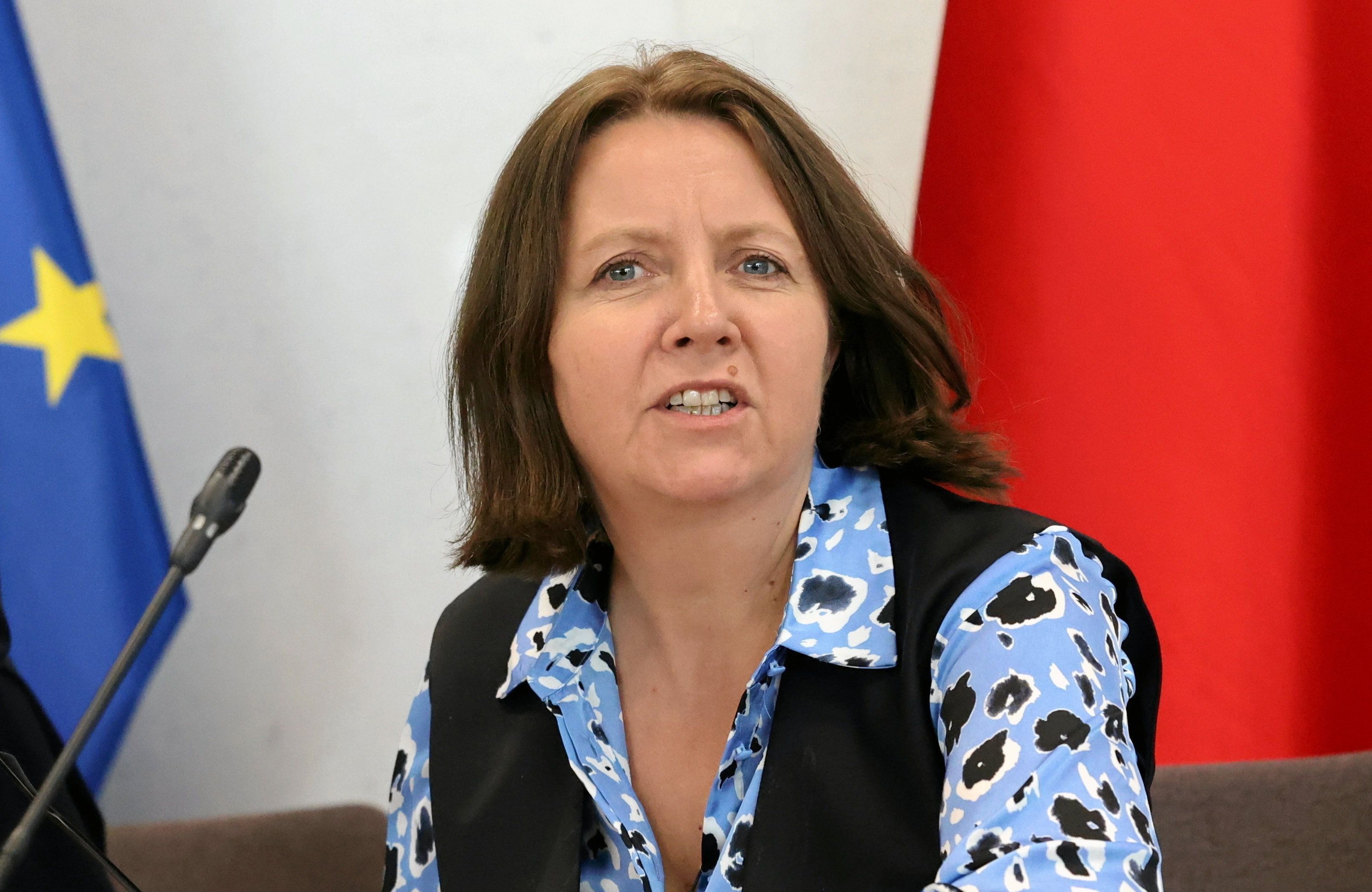 Posłanka Lichocka w kwiecistej bluzce i czarnej kamizelce na tle flag UE i Polski