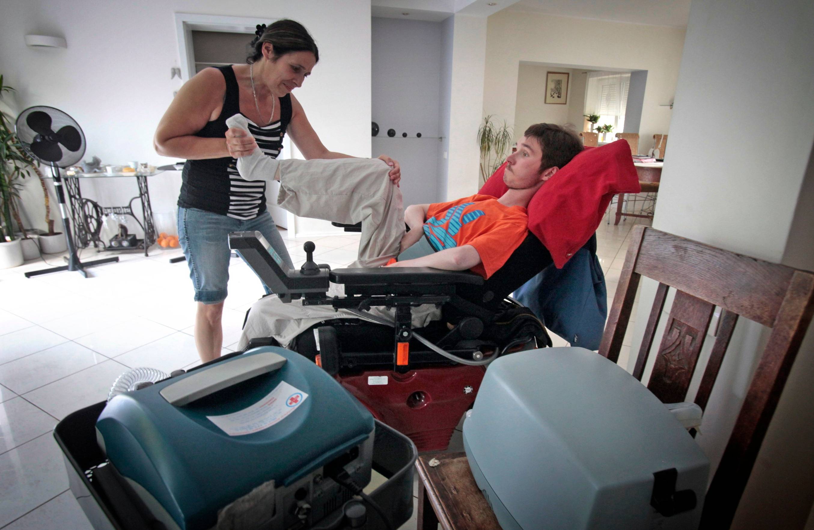 Rehabilitacja osoby z niepełnosprawnością. Obok wózka stoją specjalistyczne urzadzenia