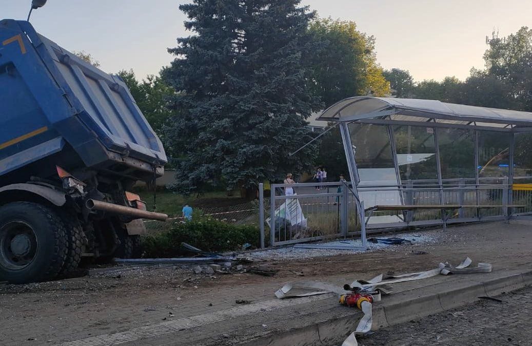 Uszkodzona po wypadku wiata przystanku autobusowego, tył ciężarówki wystający z rowu