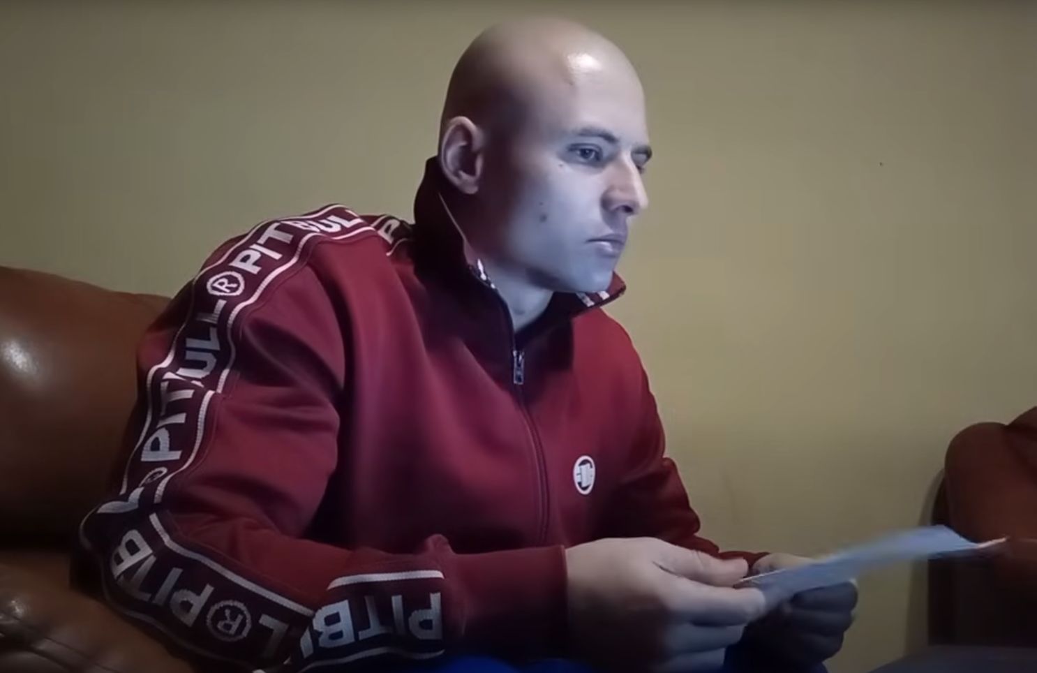 Rafał Podejma, inicjator tworzenia "patroli obywatelskich". Młody mężczyzna, łysy, w czerwonej bluzie dresowej, w ręku trzyma kartkę papieru.