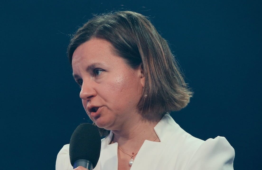 Urszula Zielińska w białej bluzce przemawia do mikrofonu. Siedzi w zielonym fotelu.