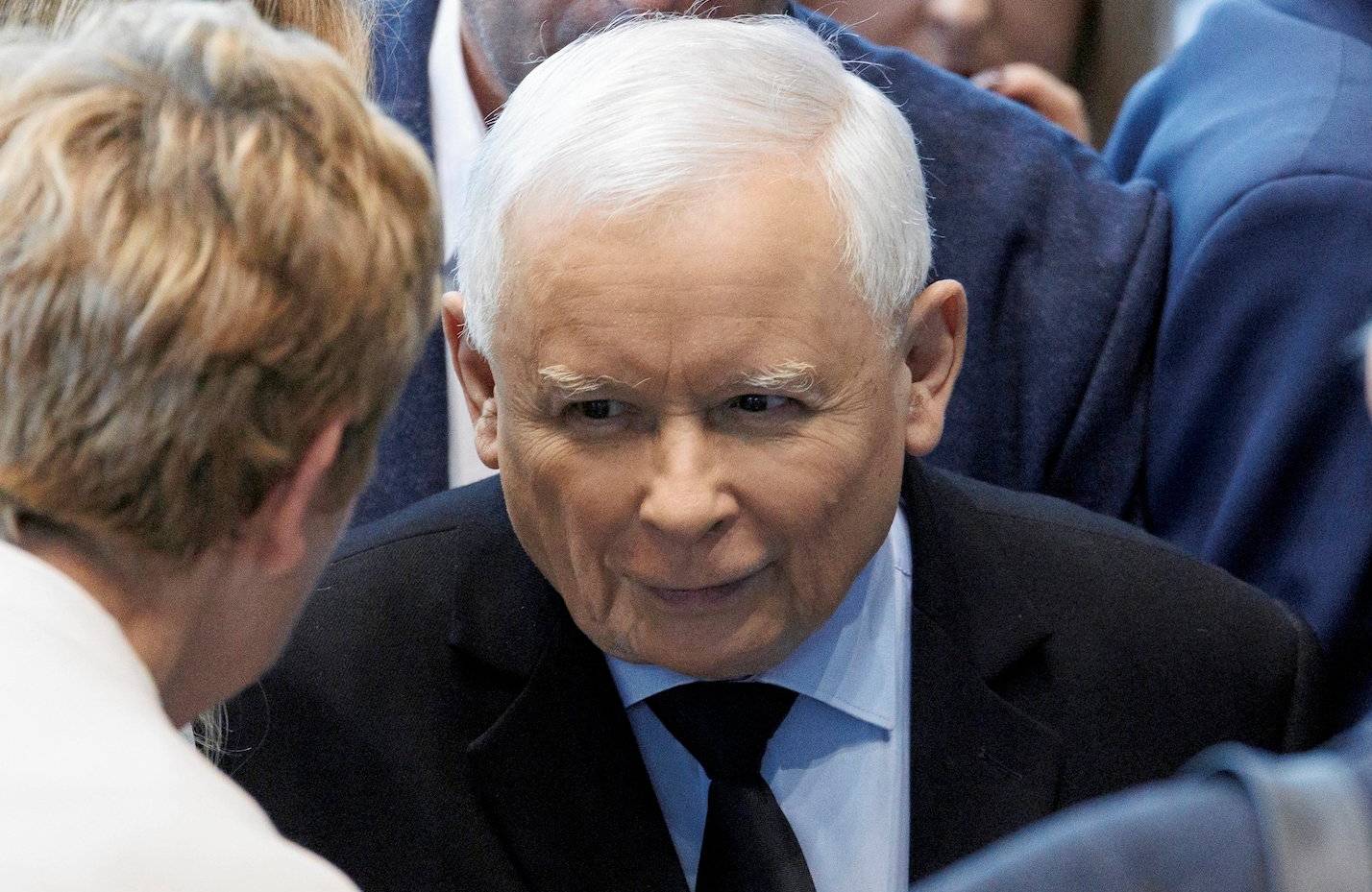 Jarosław Kaczyński rozmawia z kobietą odwróconą tyłem do obiektywu. Uśmiecha się przebiegle.