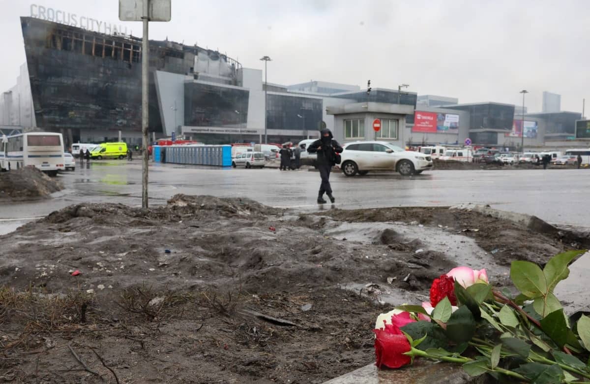 Widok na spalone centrum, na [pierwszym planie wiązanka kwiatów upamiętniająca ofiary