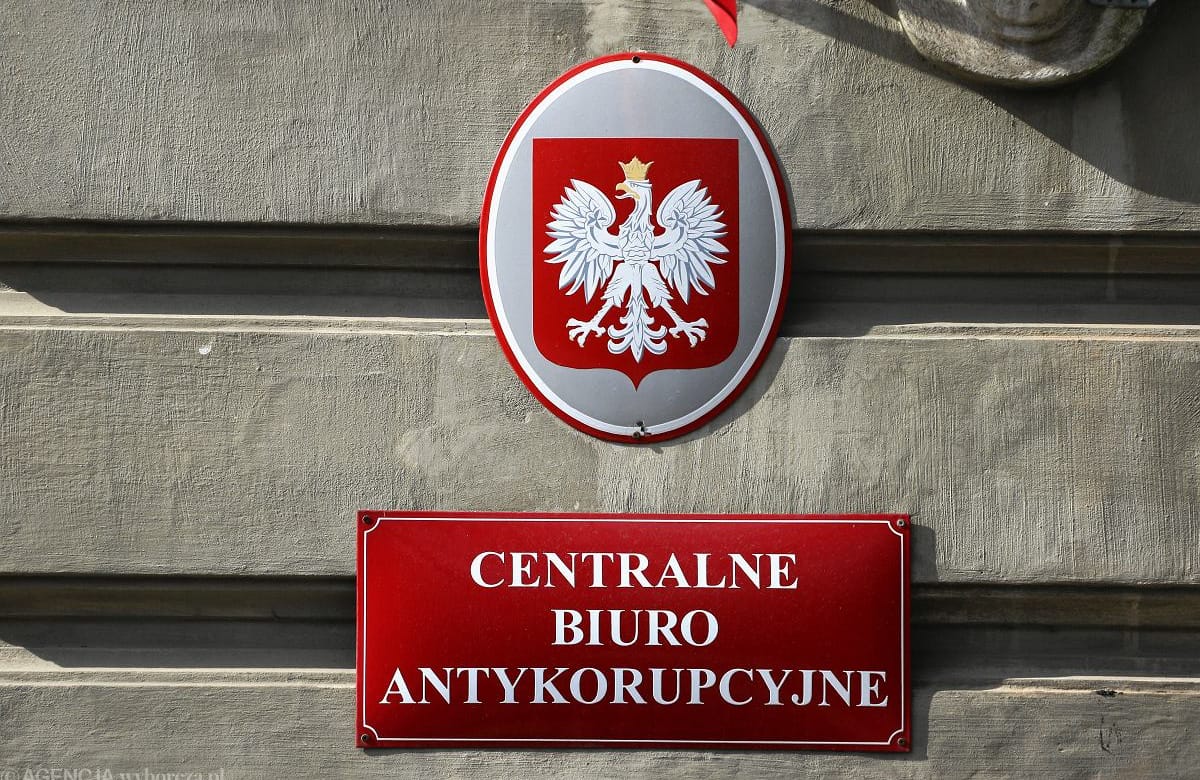 Tabliczka na budynku. Napis głosi "centralne biuro antykorupcyjne". Czerwone tło, białe litery. Nad nią jest tabliczka z godłem Polski.