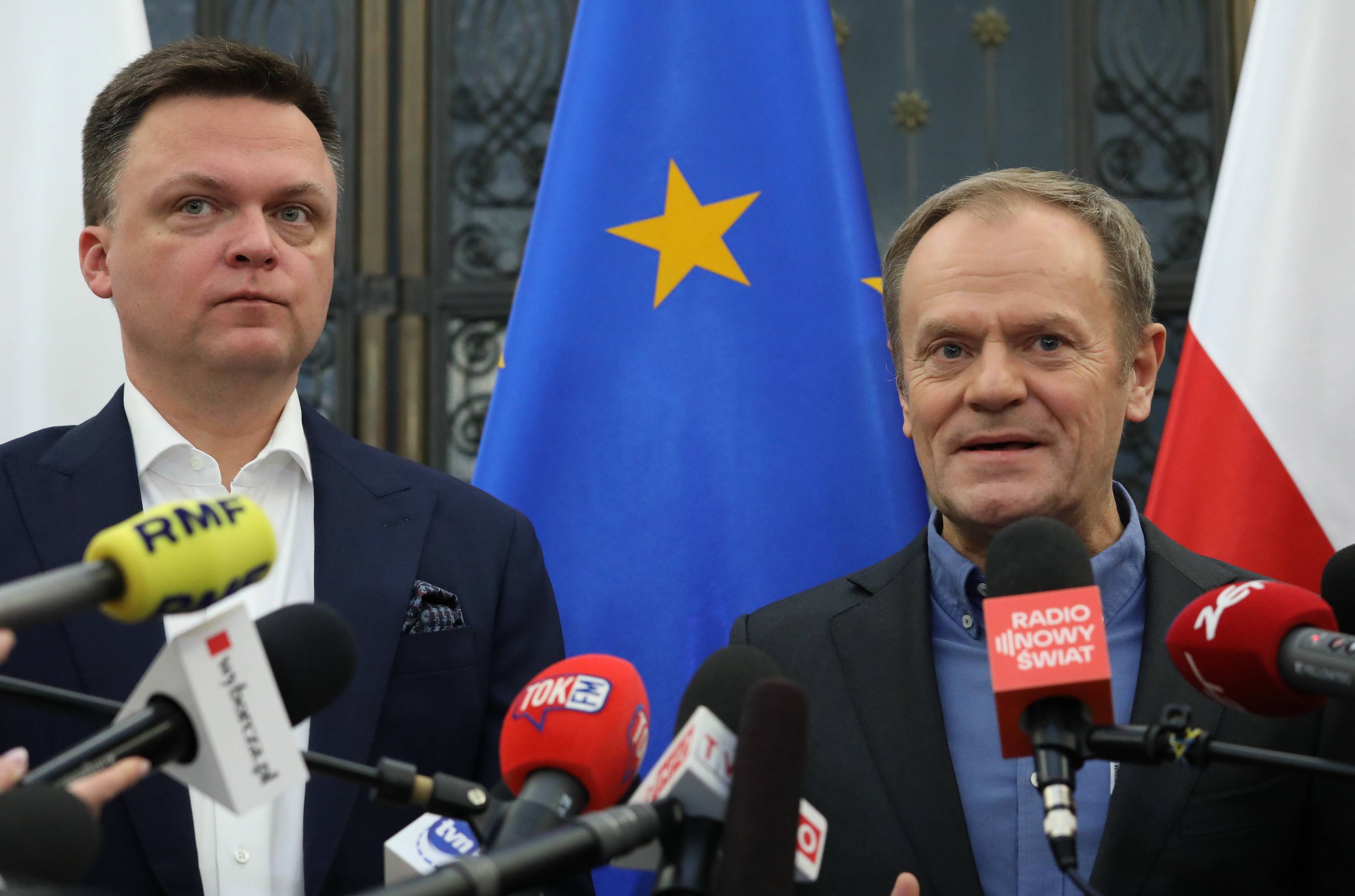 Tusk i Hołownia na tle polskich i europejskich flag