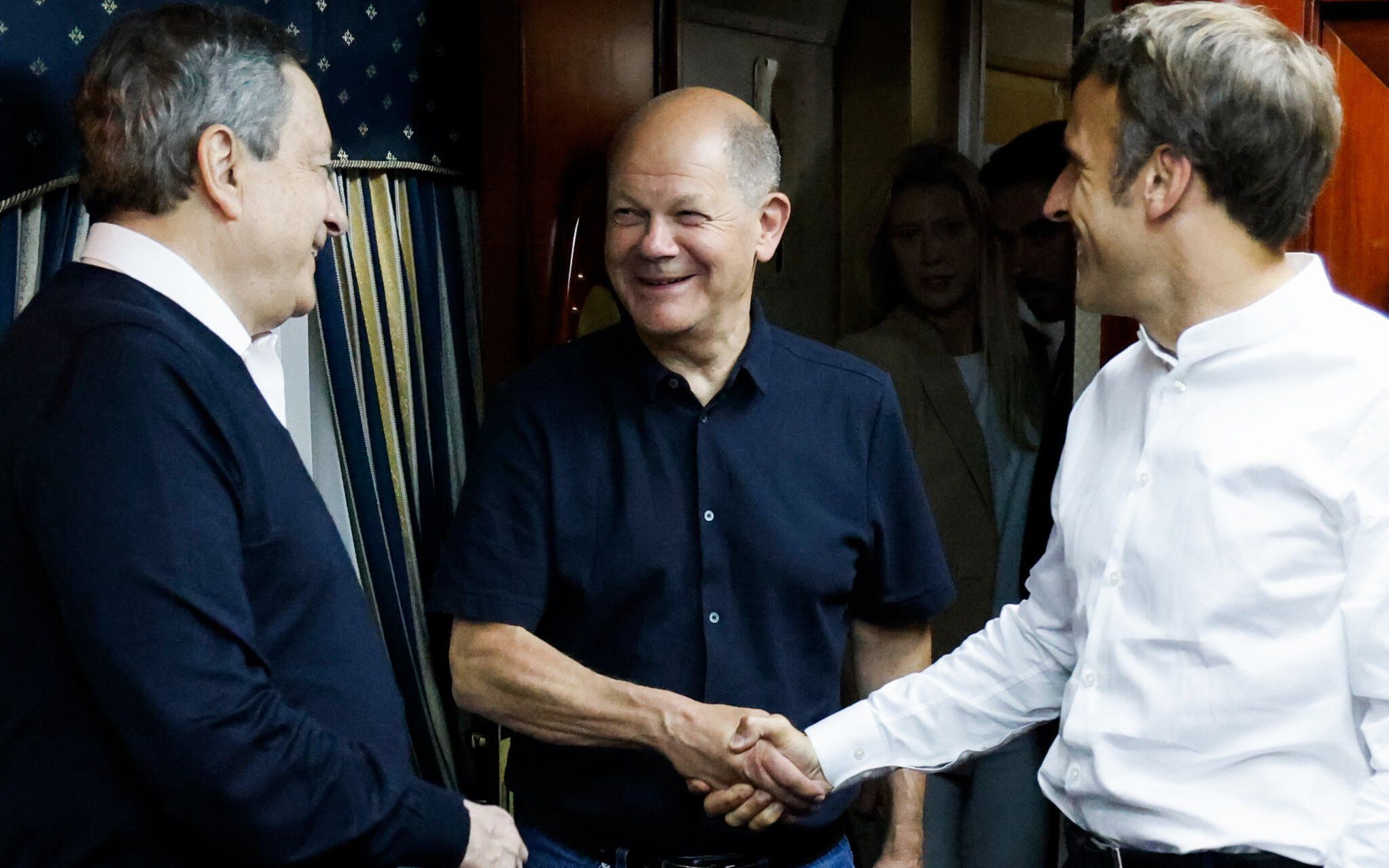French President Emmanuel Macron (R) shakes hands with German Chancellor Olaf Scholz (C) next to Italian Prime Minister Mario Draghi (L) as they travel on board a train bound to Kyiv after departing from Poland on June 16, 2022. - French President Emmanuel Macron, German Chancellor Olaf Scholz and Italian Prime Minister Mario Draghi left Poland June 16, 2022 onboard a train bound for Kyiv, an AFP reporter said. The three leaders left in the morning, according an AFP video, which showed the trio sitting together in a train compartment (Photo by Ludovic MARIN / POOL / AFP)