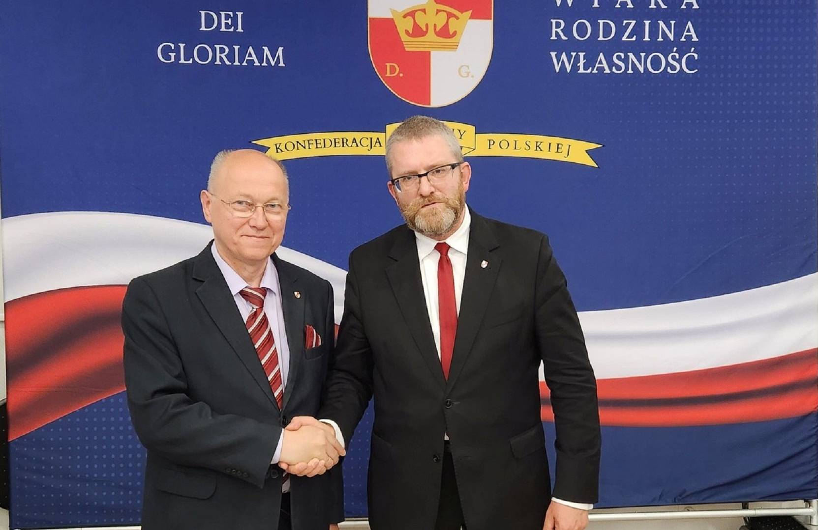 Ryszard Zajączkowski (z lewej) ze swoim politycznym liderem posłem Grzegorzem Braunem, fot. FB R. Zajączkowskiego, dwóch mężczyzn w garniturach ściska sobie dłonie, w tle logo partii Konfederacji Korony Polskiej