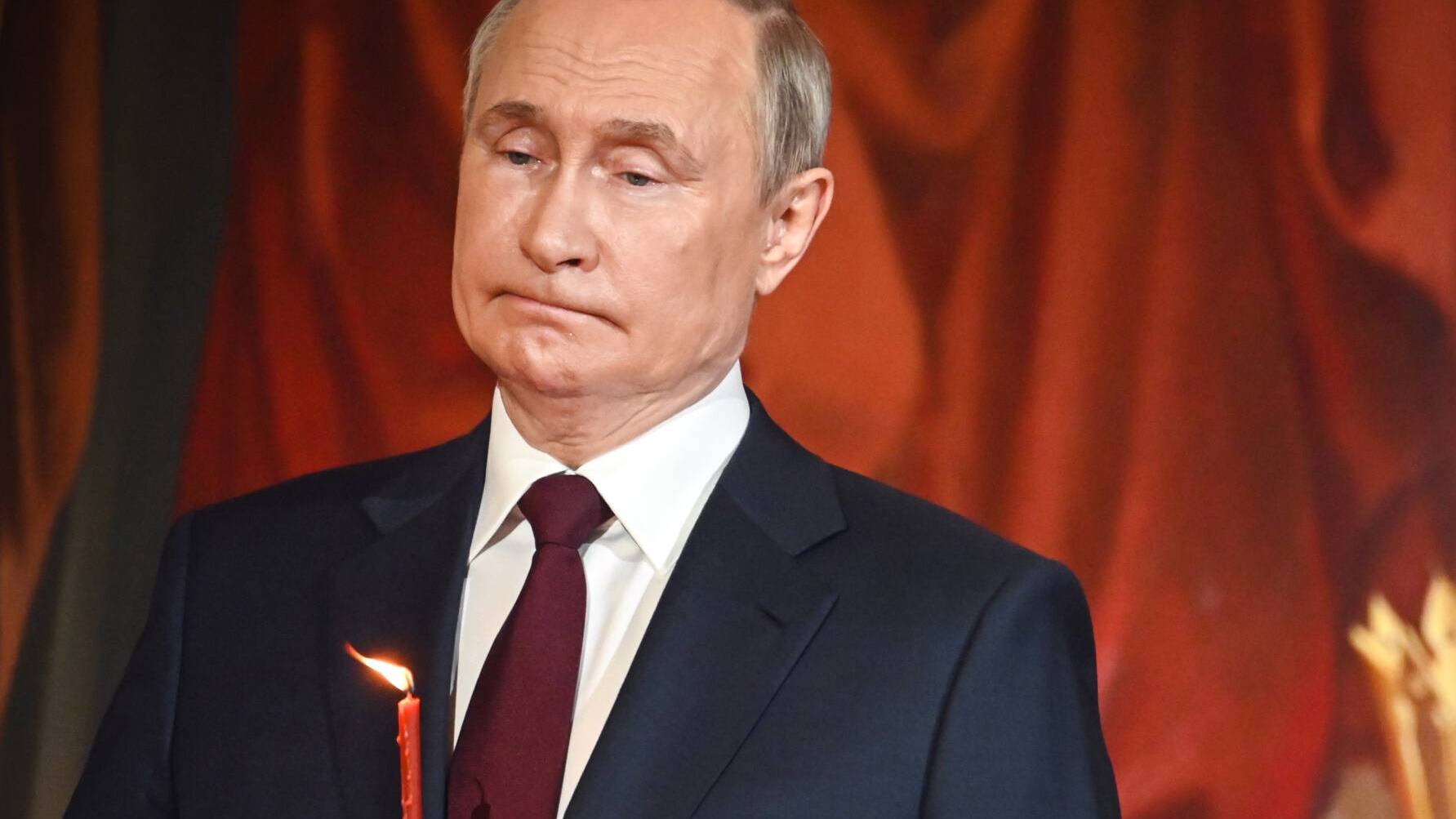 Putin w cerkwi trzyma cienką świecę w czasie nabożeństwa wielkanocnego
