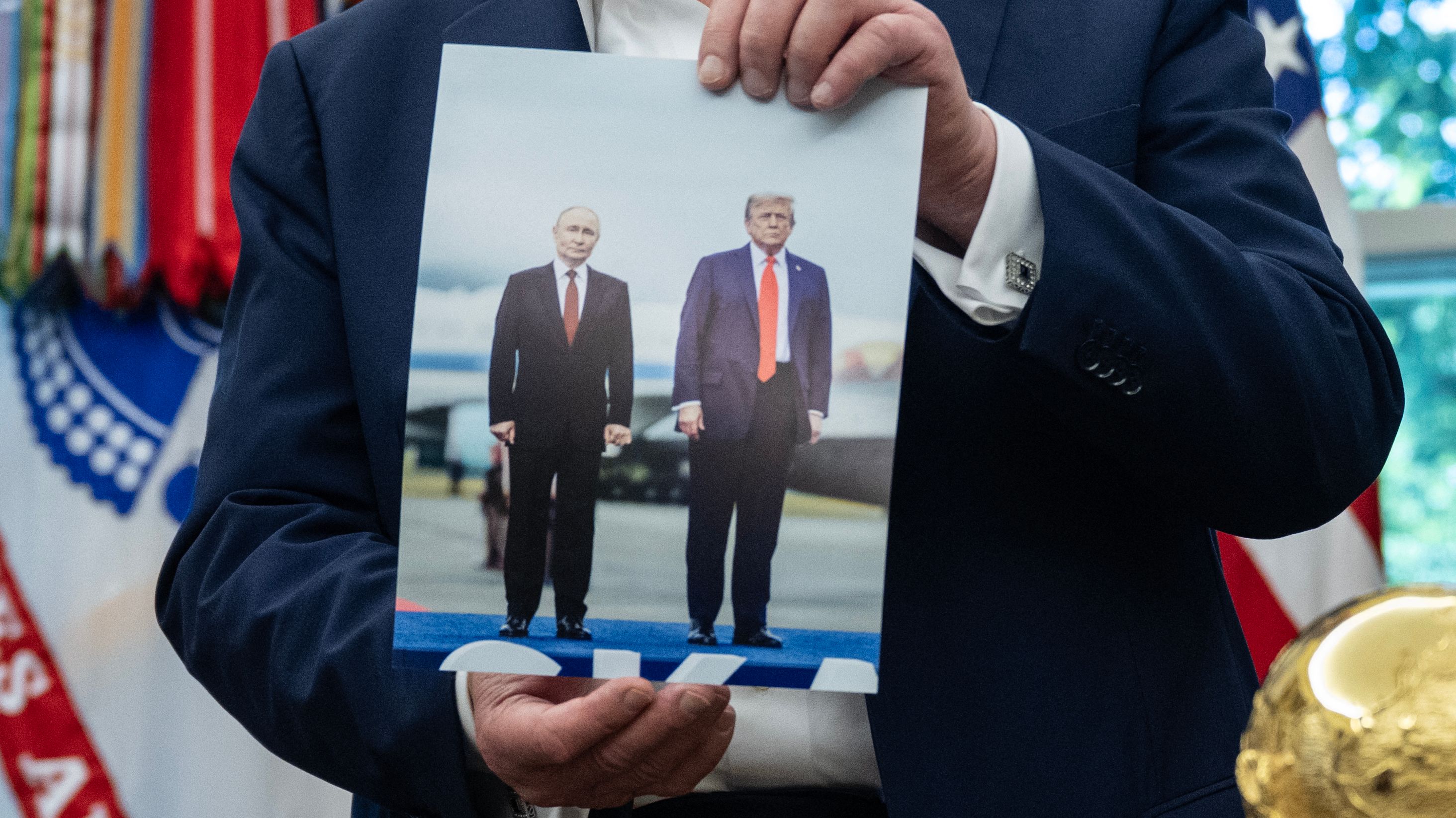 Męzczyzna trzyma fotografie dwóch męzczyz