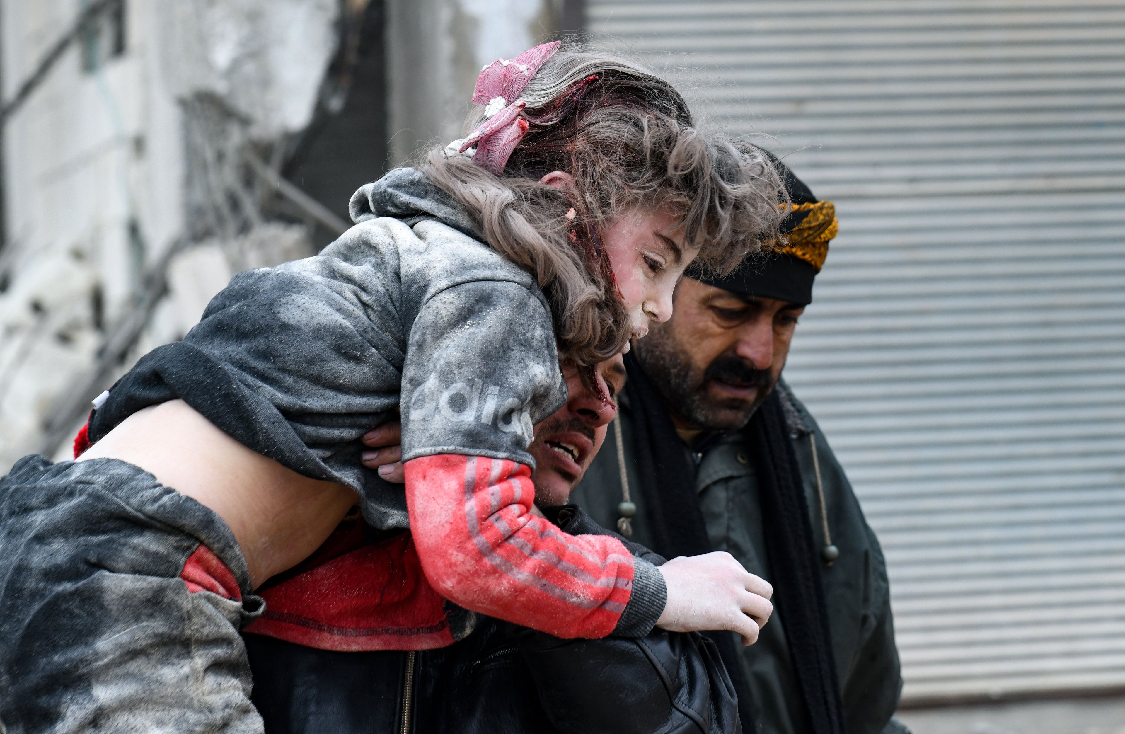 Dziewczynka, ofiara trzęsienia ziemi w Turcji i Syrii wynoszona przez mężczyznę z ruin zawalonego budynku.
