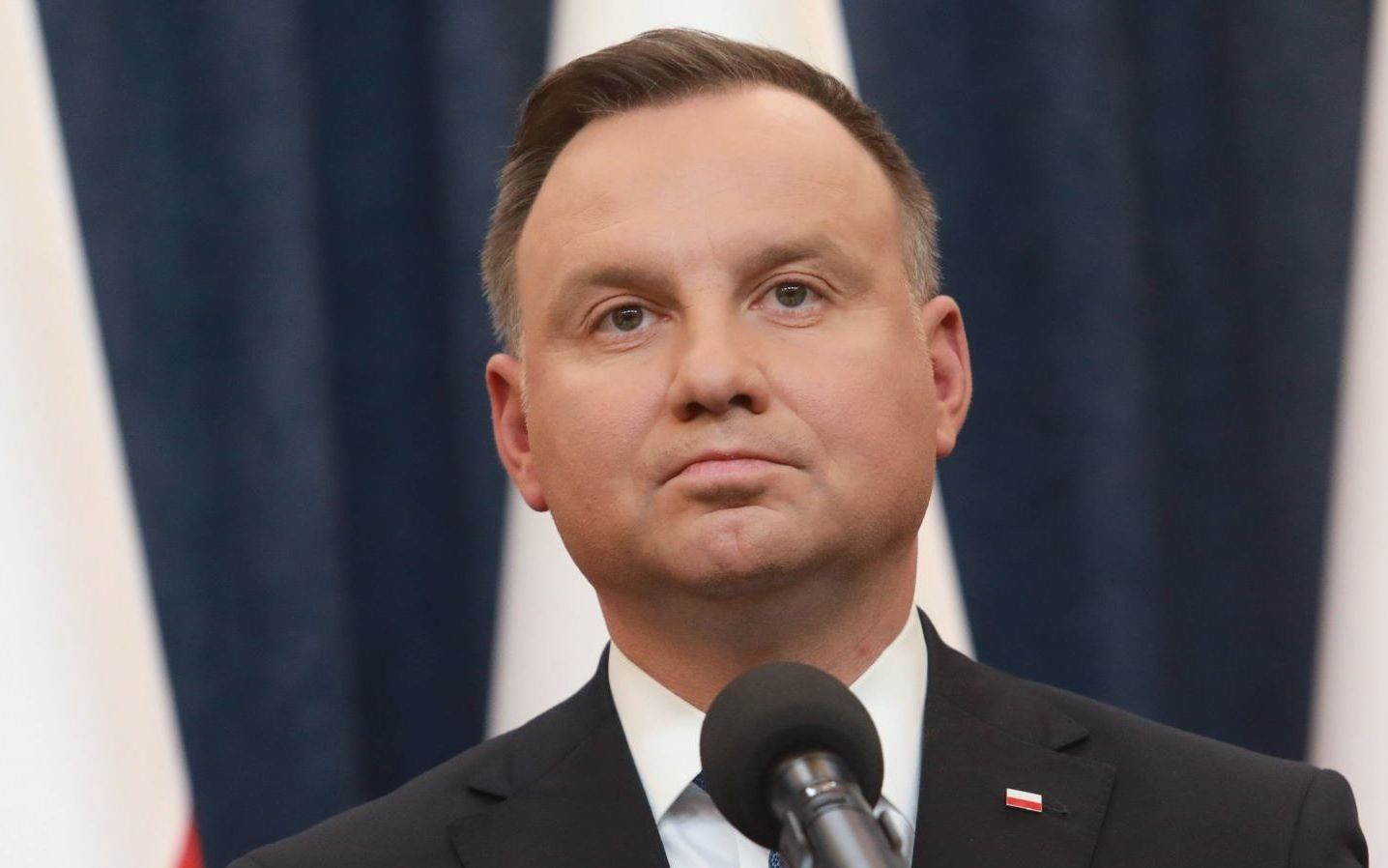 Prezydent Andrzej Duda na tle biało-czerwonych flag