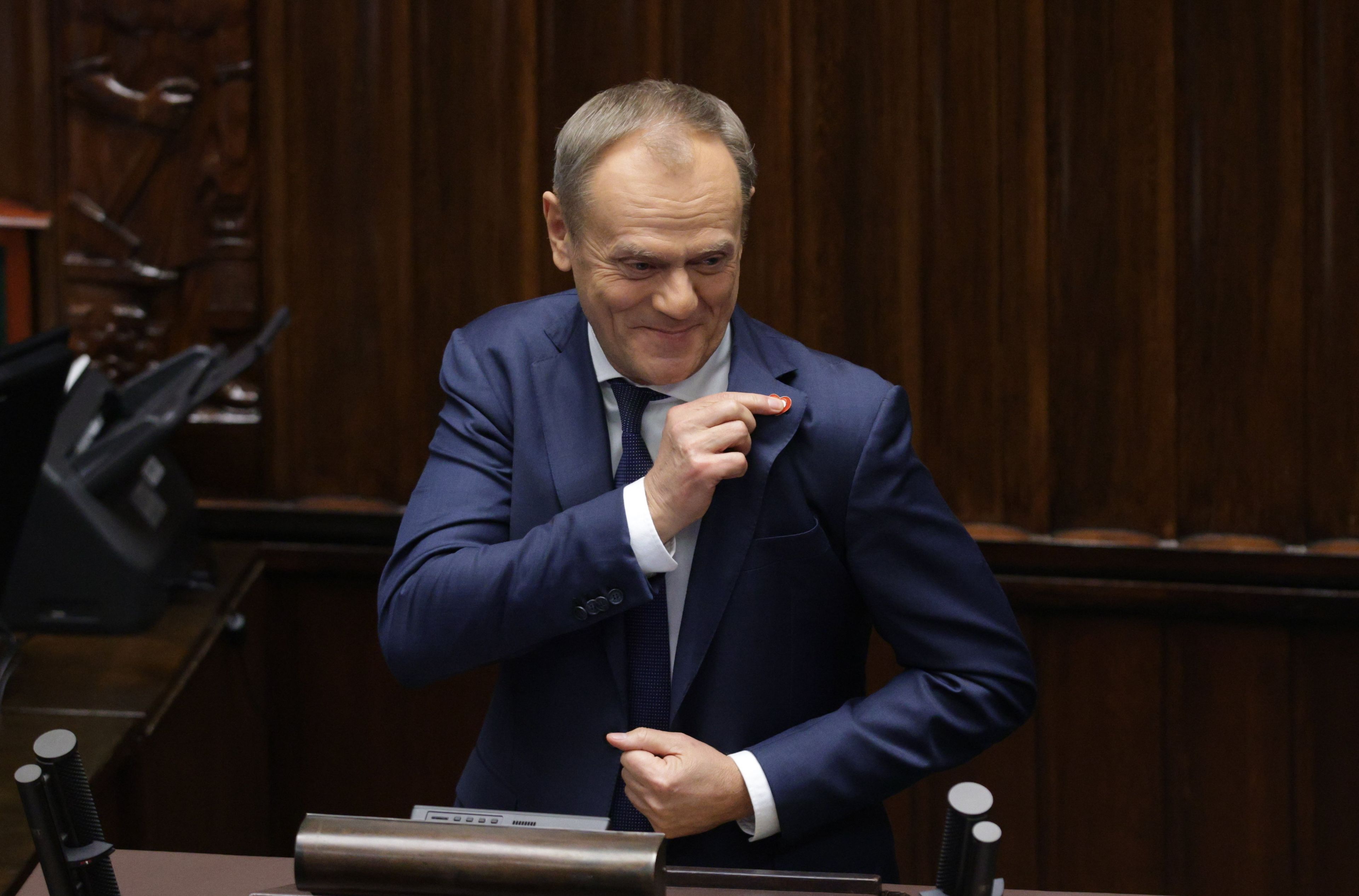 Donald Tusk na mównicy sejmowej dotyk biało-czerwonego serduszka, które ma w klapie marynarki