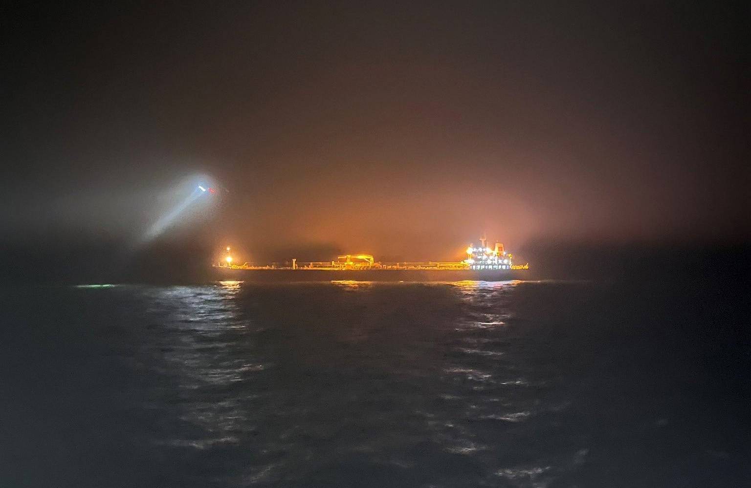Nocne zdjęcie z oddali - widać oświetlony reflektorami statek na morzu