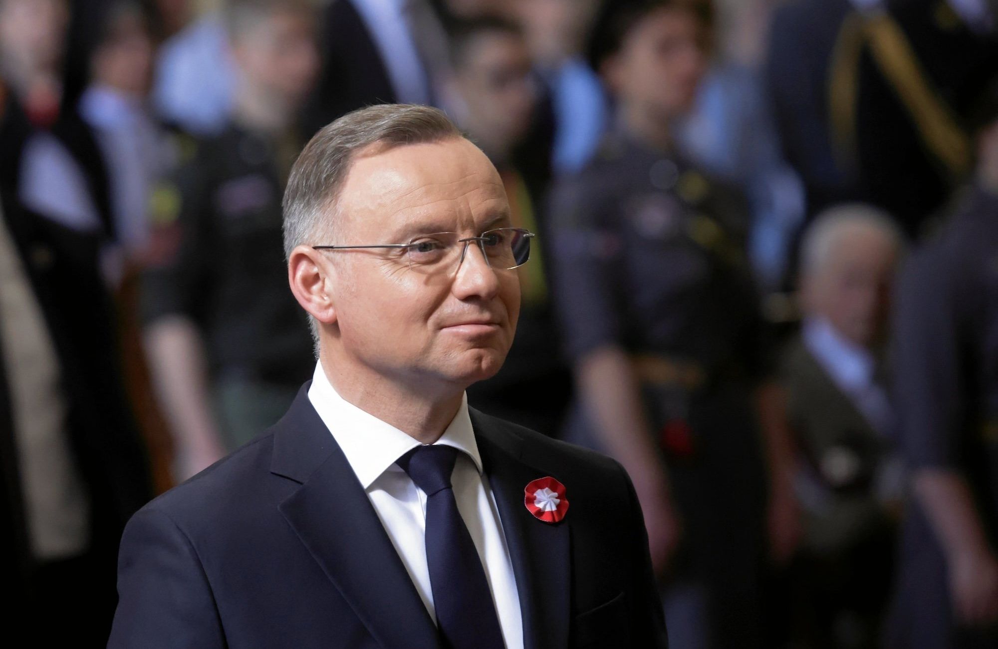 Uśmiechnięty Andrzej Duda w ciemnym garniturze i krawacie.