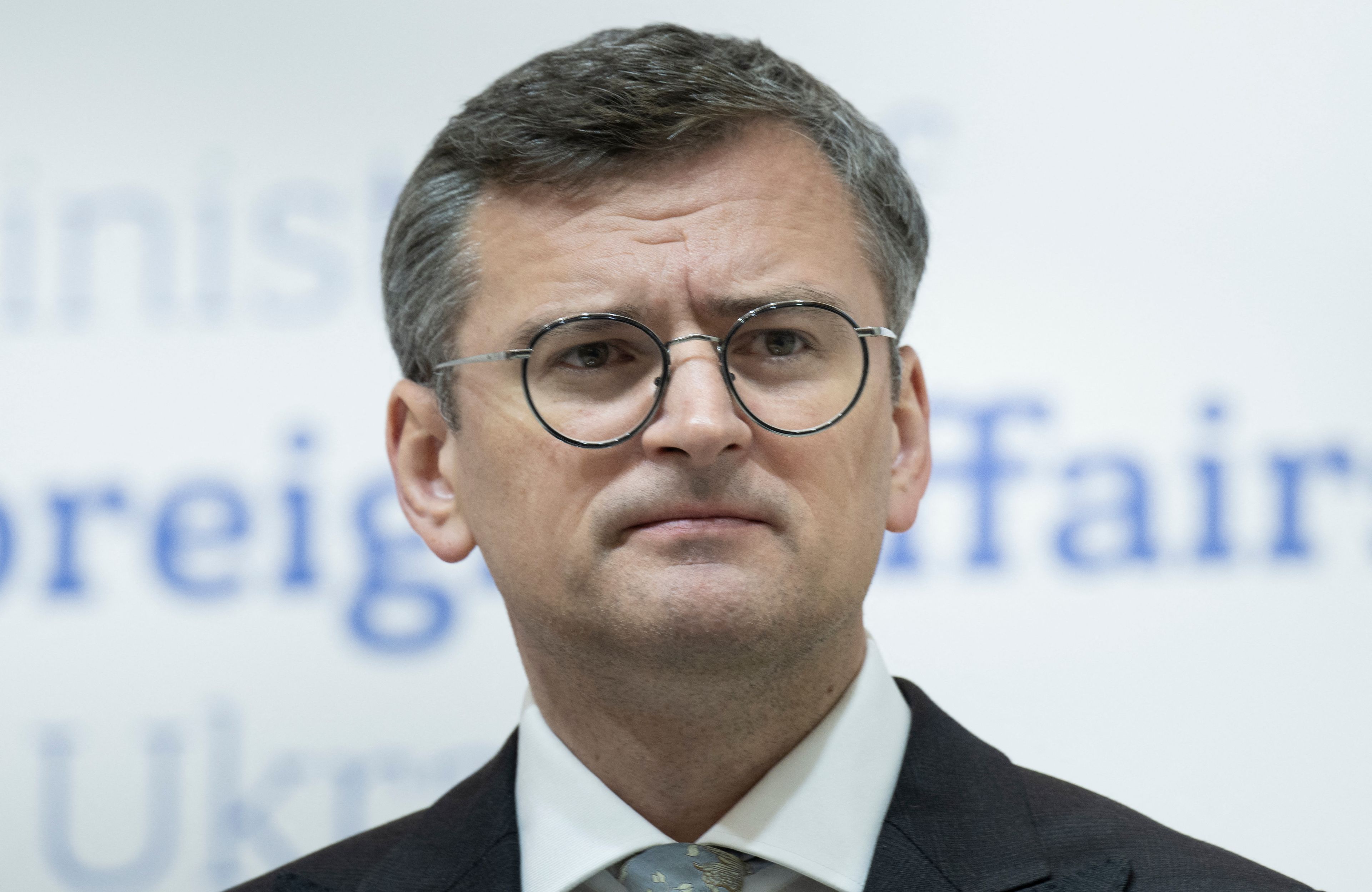 Na zdjęciu jest mężczyzna w garniturze i okularach. Na wygląd ma ok. 45 lat. Ma krótkie czarne z siwym włosy