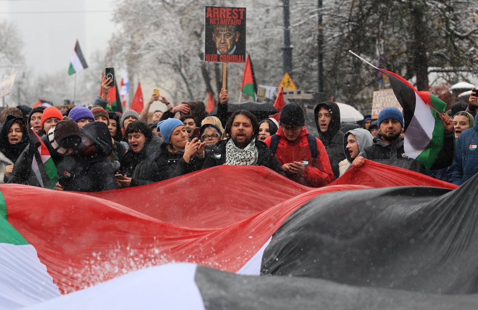 Uczestnicy propalestyńskiej demonstracji w Warszawie trzymają dużą flagę Palestyny