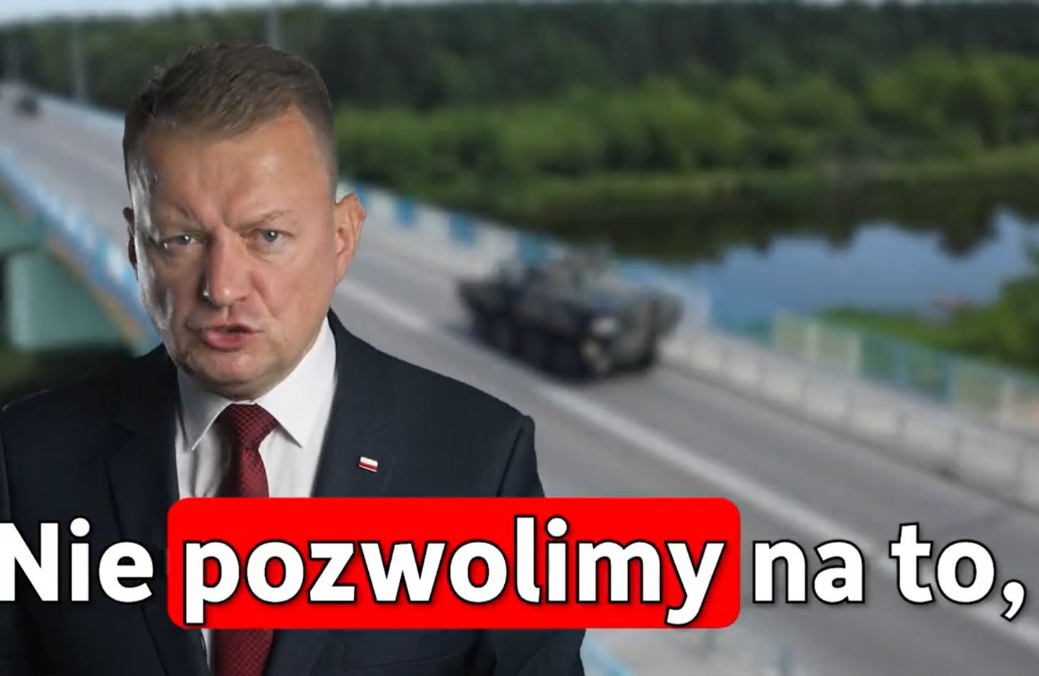 Mężczyzna w garniturze mówi "nie pozwolimy na to" na tle obrazu jadącego drogą czołgu