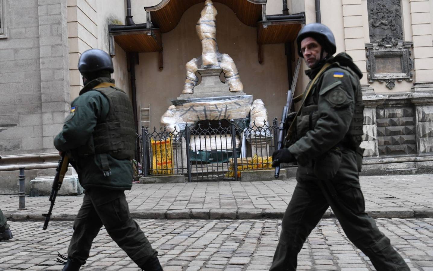 Ukrainian servicemen walk past wrapped statues at the Archcathedral Basilica of the Assumption of the Blessed Virgin Mary also known as Latin Cathedral in Lviv western Ukraine, on March 5, 2022. (Photo by Daniel LEAL / AFP)