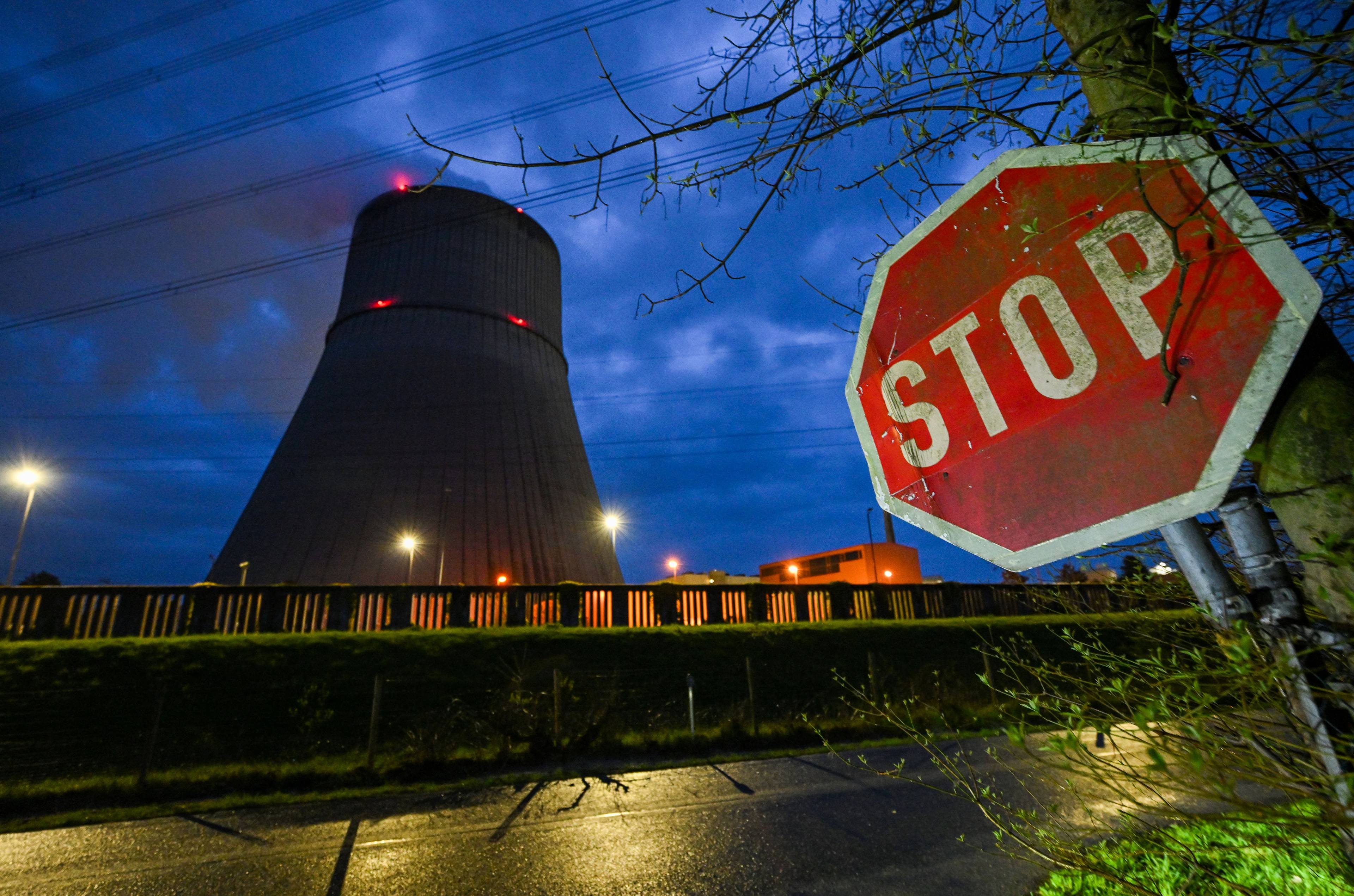 Zdjęcie pokazuje znak drogowy Stop w pobliżu wieży chłodniczej elektrowni jądrowej