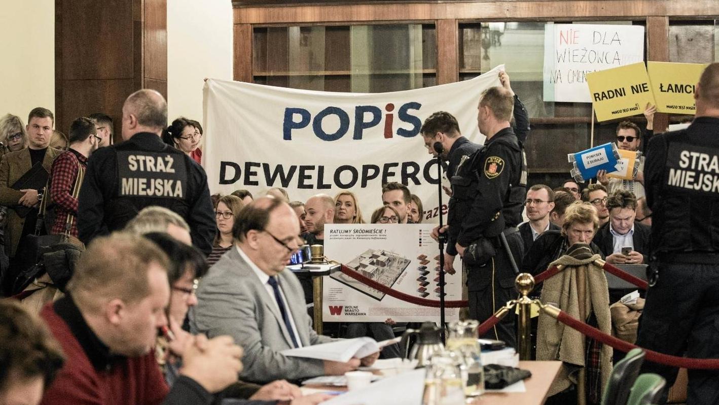 Protestujący z transparentem "POPiS deweloperów" na sesji rady miasta