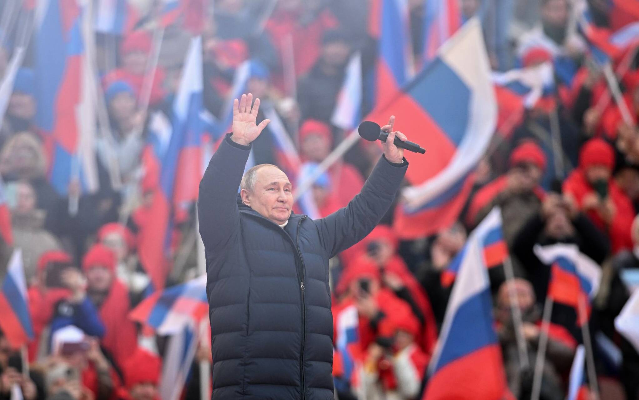 Russian President Vladimir Putin greets the audience as he attends a concert marking the eighth anniversary of Russia's annexation of Crimea at the Luzhniki stadium in Moscow on March 18, 2022. (Photo by Ramil SITDIKOV / POOL / AFP)