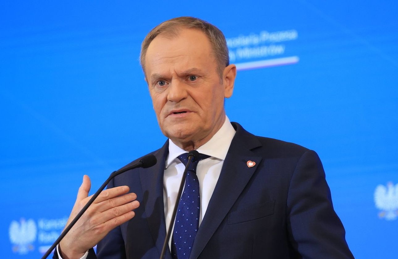 Donald Tusk podczas konferencji prasowej w Kancelarii Premiera. Przemawia na tle niebieskiego panelu z nazwą KPRM