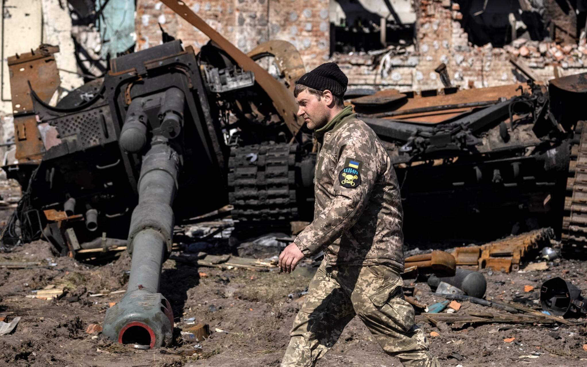 A Ukrainian serviceman walks between damaged Russian army tank and rubble of a destroyed building in the northeastern city of Trostyanets', on March 29, 2022. - Ukraine said on March 26, 2022 its forces had recaptured the town of Trostyanets, near the Russian border, one of the first towns to fall under Moscow's control in its month-long invasion. (Photo by FADEL SENNA / AFP)