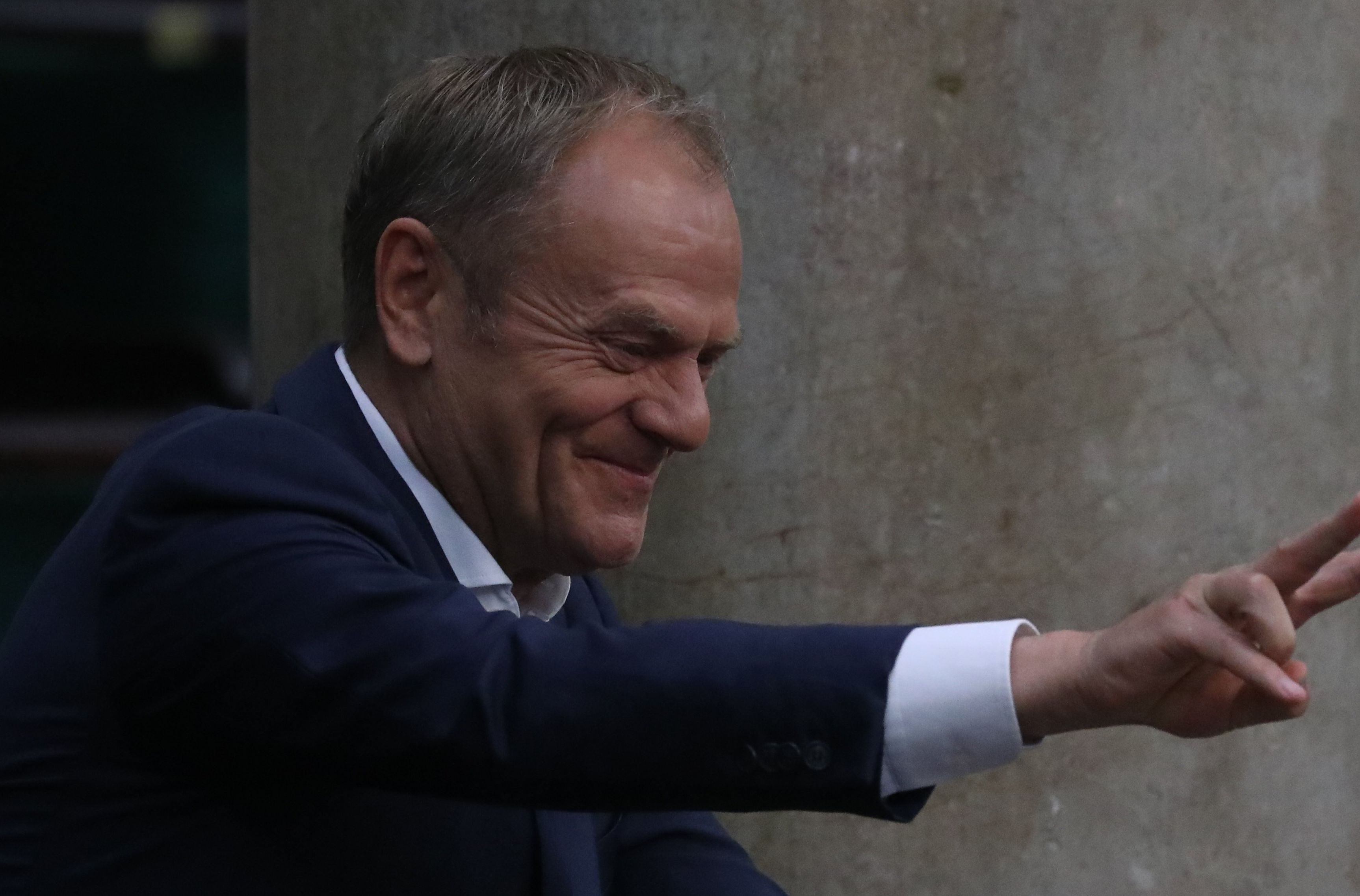 Uśmiechnięty Tusk pokazujący znak „V"