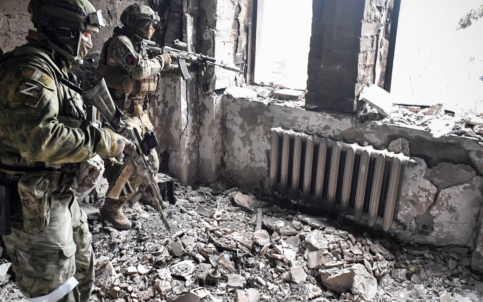 Two Russian soldiers patrol in the Mariupol drama theatre, bombed last March 16, in Mariupol on April 12, 2022, as Russian troops intensify a campaign to take the strategic port city, part of an anticipated massive onslaught across eastern Ukraine, while Russia's President makes a defiant case for the war on Russia's neighbour. - *EDITOR'S NOTE: This picture was taken during a trip organized by the Russian military.* (Photo by Alexander NEMENOV / AFP)