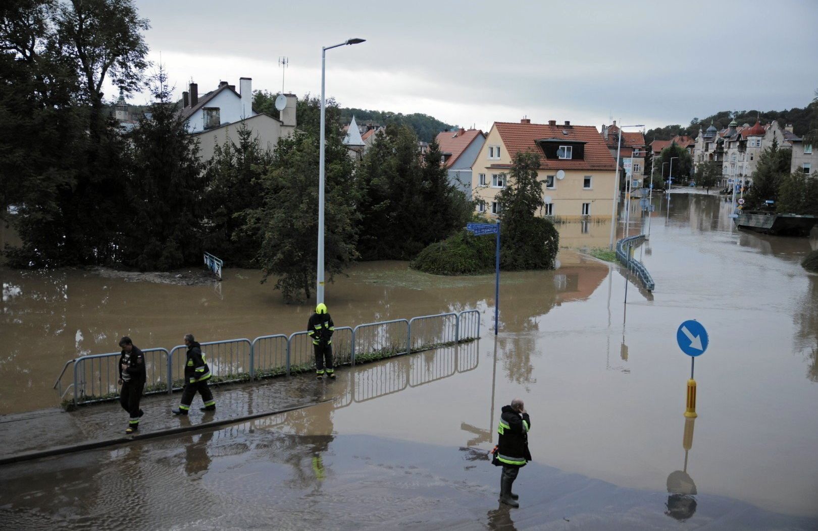 na zdjęciu są trzy osoby. Ulice są zalene brudną wodą