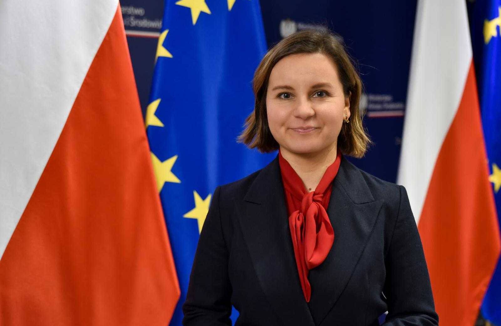Kobieta stoi na tle flag Polski i UE