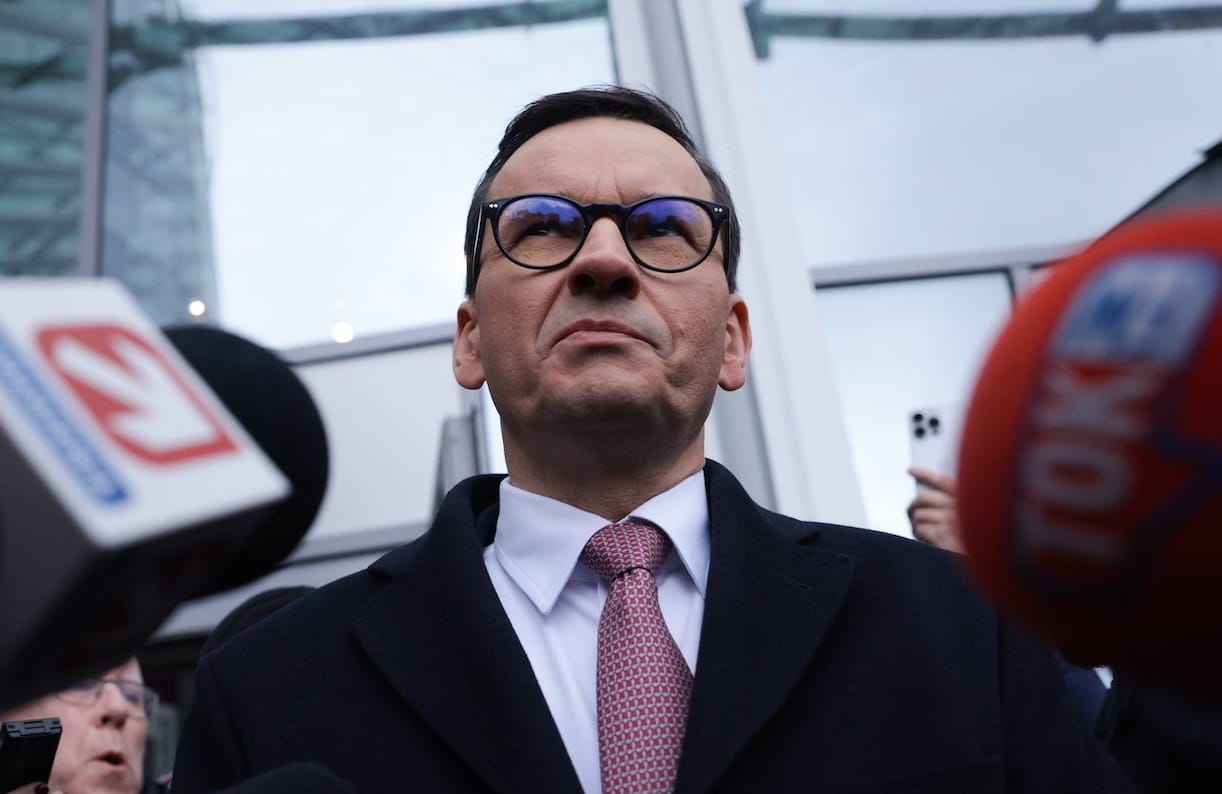 Mateusz Morawiecki pod siedzibą TVP, wokół mikrofony mediów.