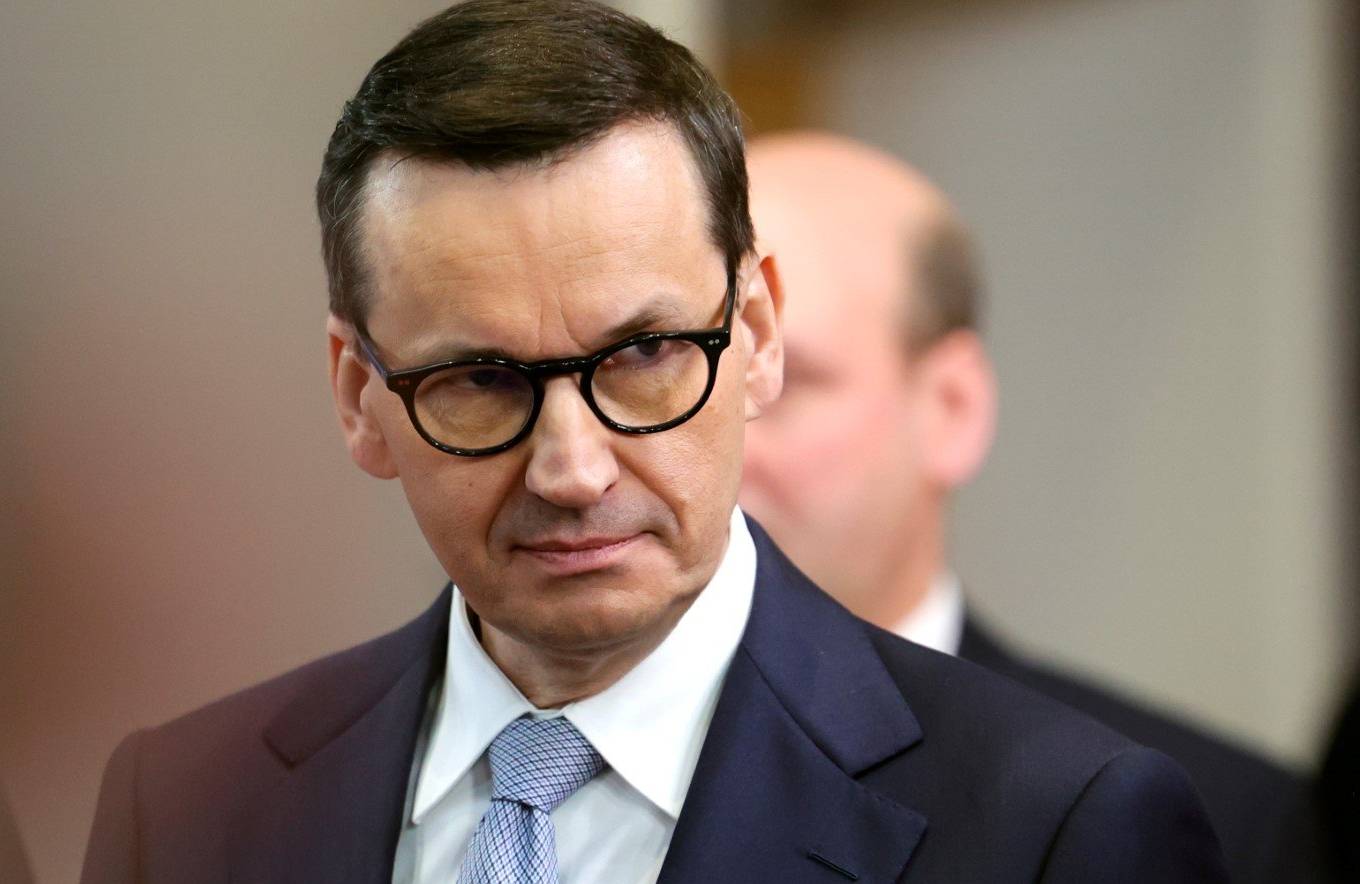 Premier Morawiecki patrzy w bok z groźną albo smutna miną