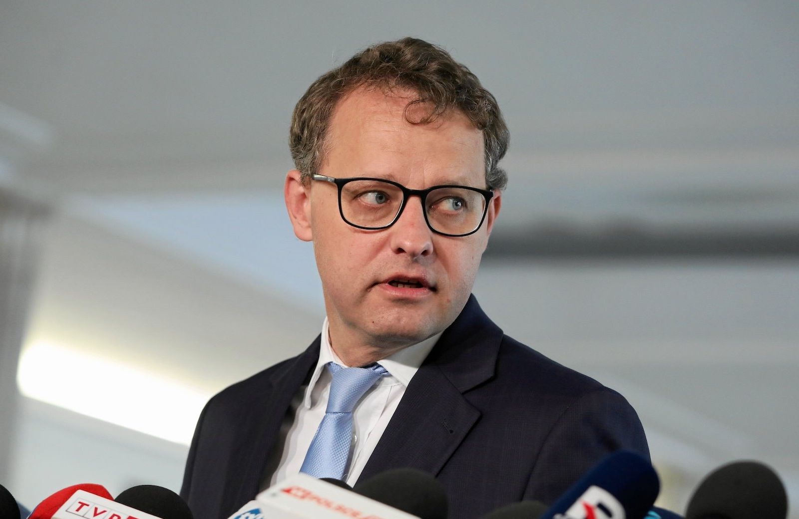 Mężczyzna w okularach przed mikrofonami