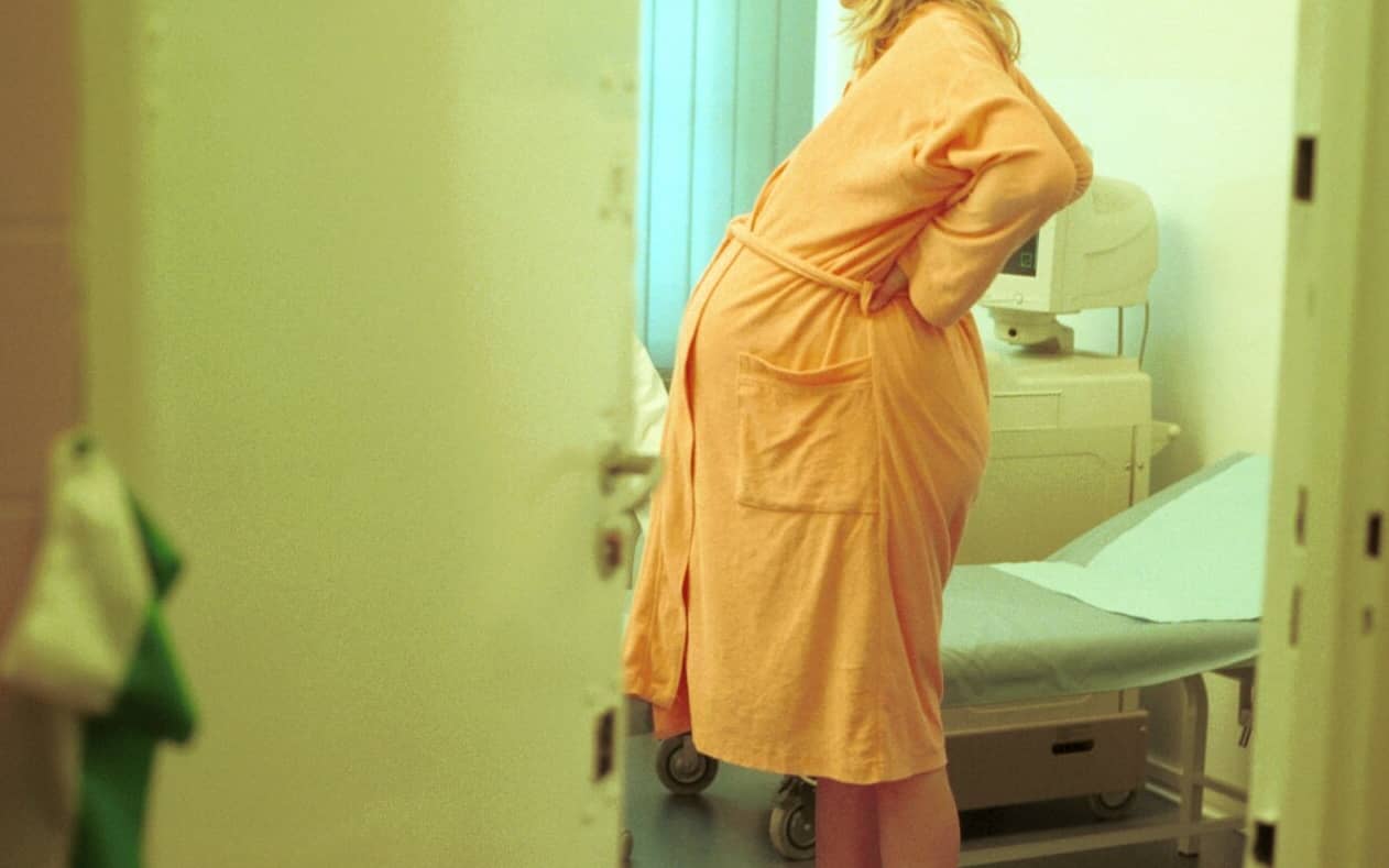 Kobieta w ciąży stoi w pokoju szpitalnym
