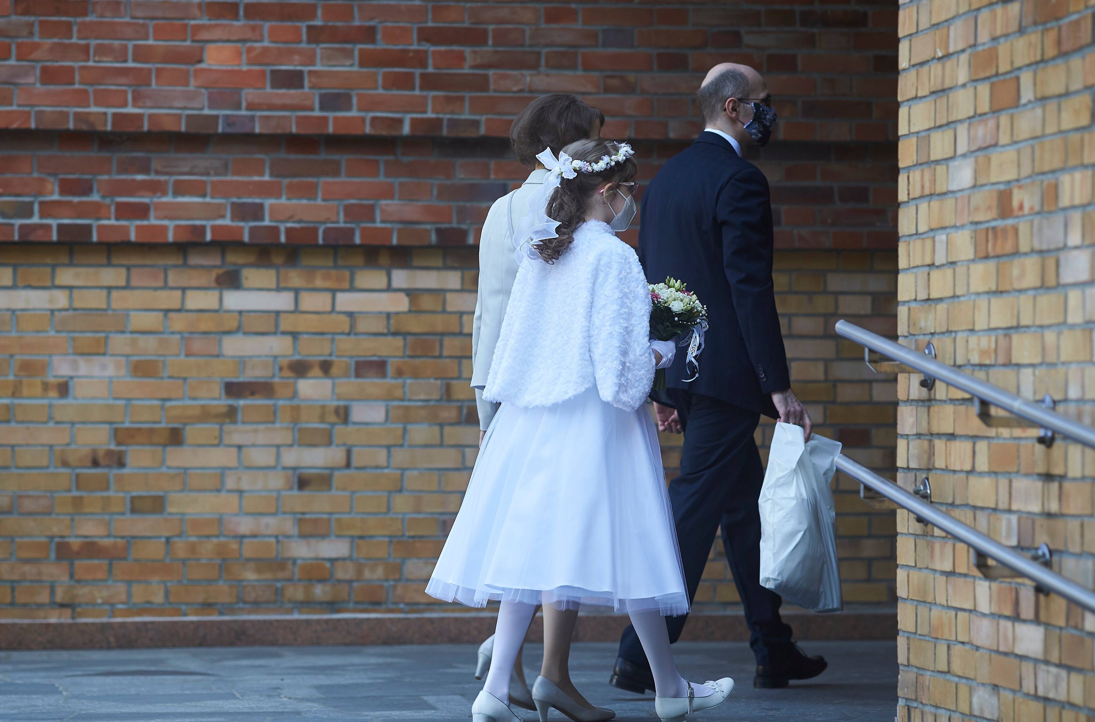 Na zdjęciu: dwie dziewczynki ubrane w białe alby i wianki wchodzą do kościoła.