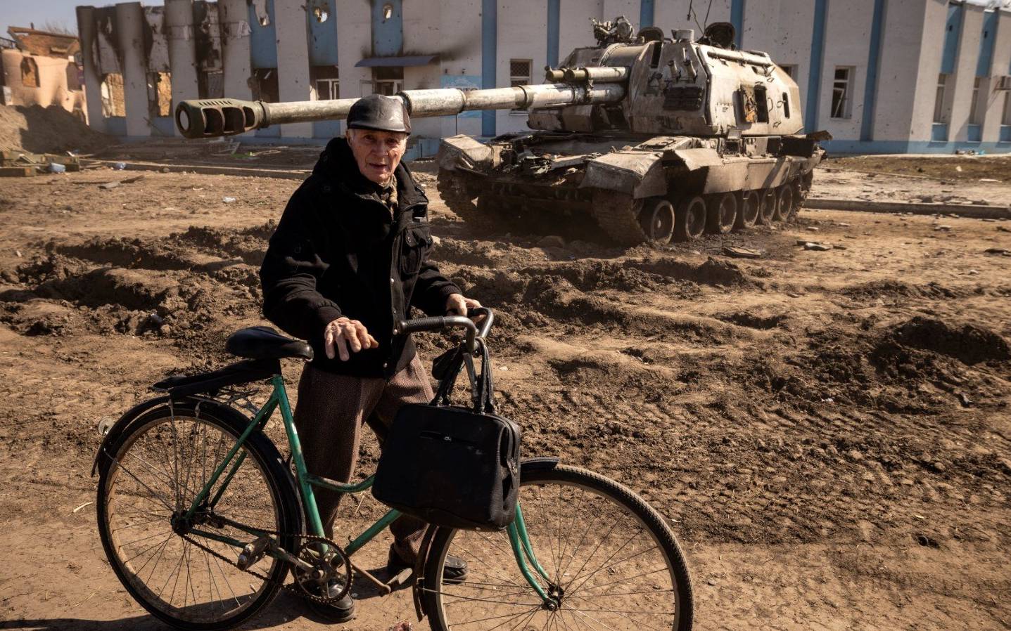 A cyclist pushes his bike near a damaged armored vehicle in the northeastern city of Trostianets, on March 29, 2022. - Ukraine said on March 26, 2022 its forces had recaptured the town of Trostianets, near the Russian border, one of the first towns to fall under Moscow's control in its month-long invasion. (Photo by FADEL SENNA / AFP)