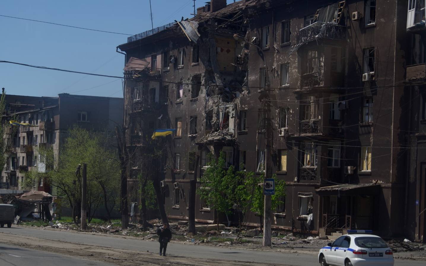 A person walks along a street past a charred residential building in the city of Mariupol on April 29, 2022, amid the ongoing Russian military action in Ukraine. (Photo by Andrey BORODULIN / AFP)