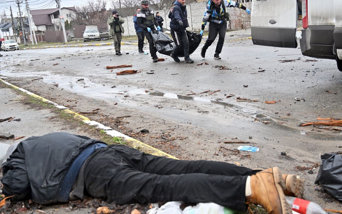 EDITORS NOTE: Graphic content / Communal workers carry a civilian in a body bag in the town of Bucha, not far from the Ukrainian capital of Kyiv on April 3, 2022. - US and NATO leaders voiced shock and horror at new evidence of atrocities against civilians in Ukraine, and warned that Russian troop movements away from Kyiv did not signal a withdrawal or end to the violence. (Photo by Sergei SUPINSKY / AFP)